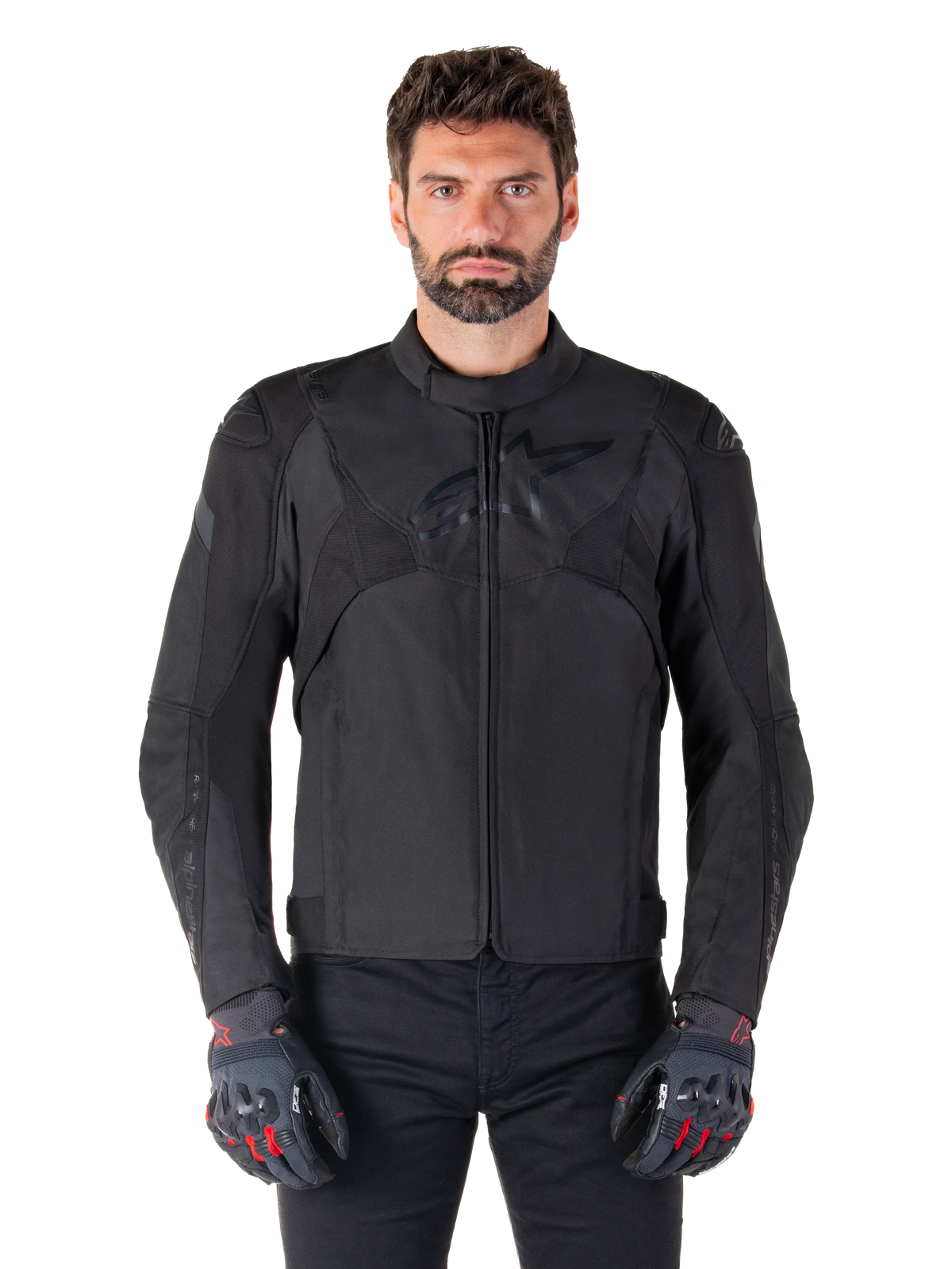 Giacca impermeabile Alpinestars T-Jaws V4, giacca da moto sportiva nera, indossata da un uomo con guanti neri e dettagli rossi, spalle e braccia rinforzate, design elegante con logo discreto sul petto, abbigliamento da moto in tessuto per tutte le stagioni