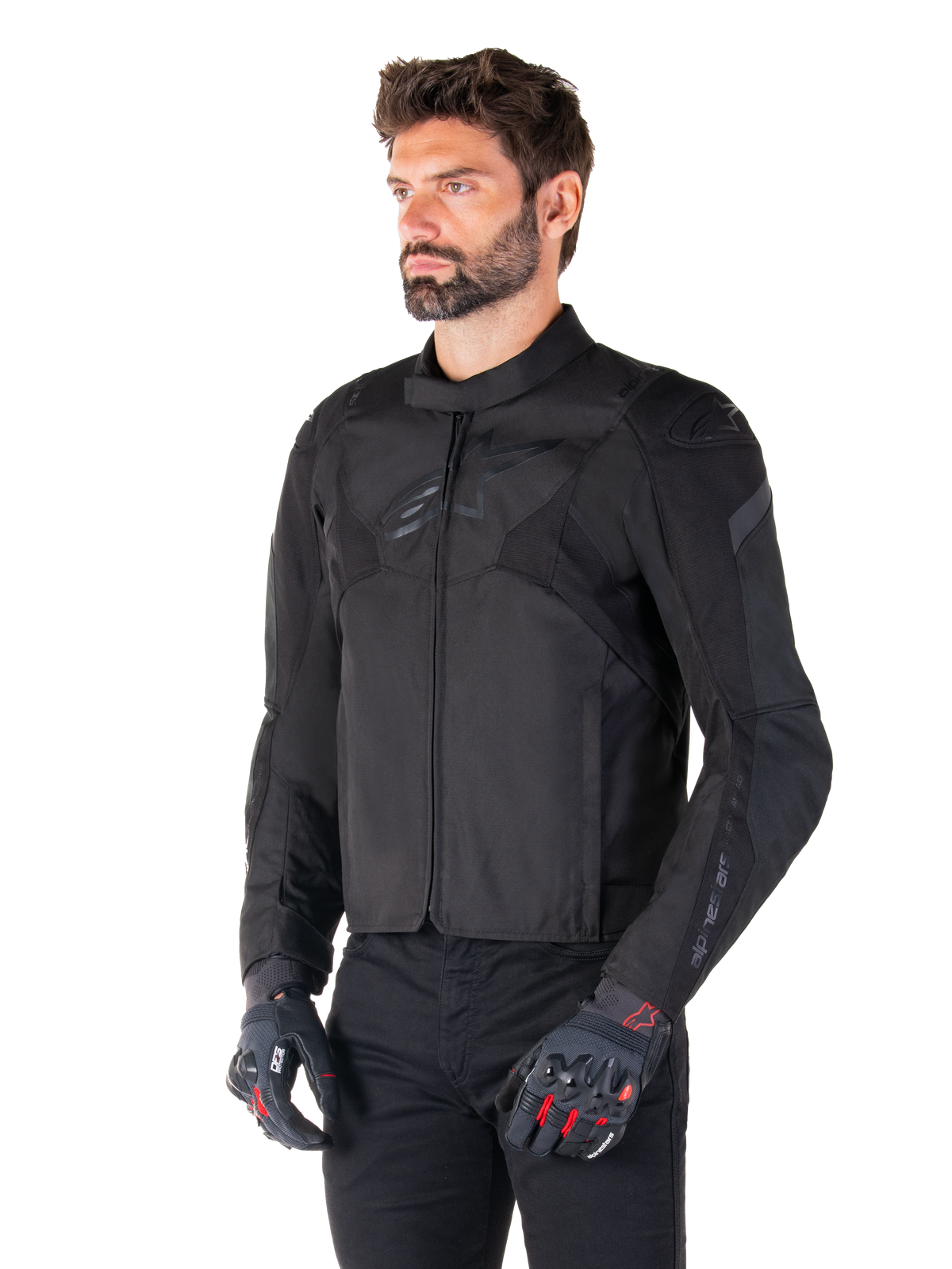 Motociclista che indossa la giacca impermeabile Alpinestars T-Jaws V4 in Black Black, abbinata a pantaloni neri e guanti protettivi, caratterizzata da una vestibilità sportiva, loghi Alpinestars tonali sul petto e sulle spalle e una struttura in tessuto ad alte prestazioni.