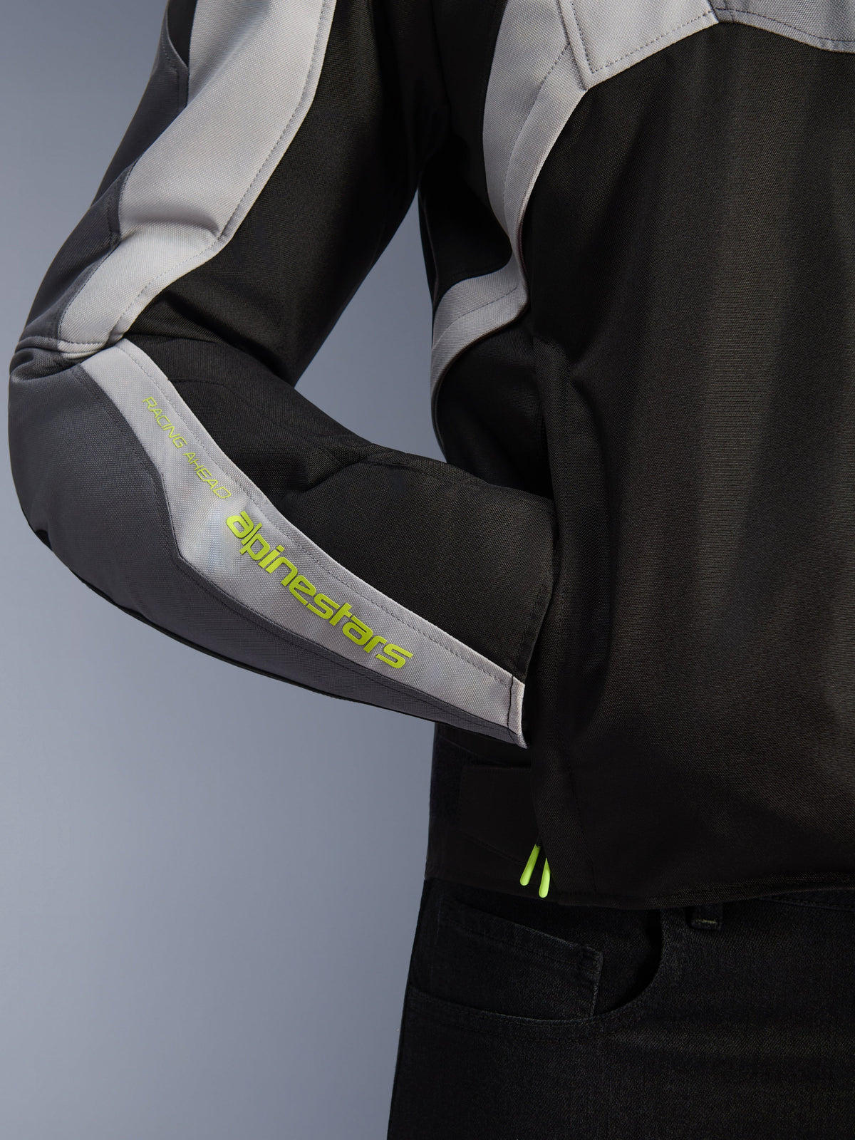 Alpinestars Giacca Impermeabile T-Jaws V4, giacca da moto, nero, grigio ghiaccio e grigio scuro, dettaglio ravvicinato della manica con marchio Alpinestars giallo fluorescente, materiale tessile con tasca laterale e design multi-pannello
