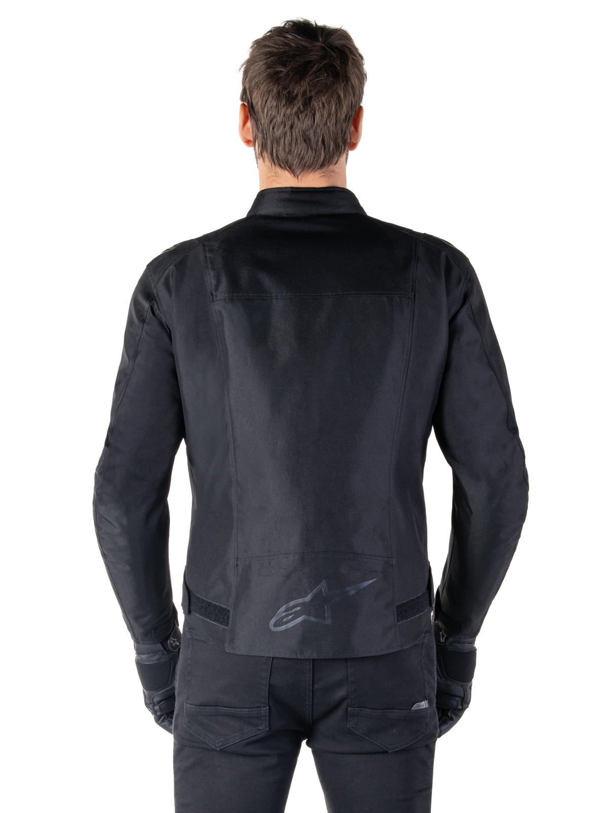 Giacca Alpinestars T-SPS V2 Waterproof, nero, vista posteriore con silhouette dal taglio sportivo, logo Alpinestars riflettente sulla parte bassa della schiena e parte posteriore allungata per una maggiore copertura durante la guida.