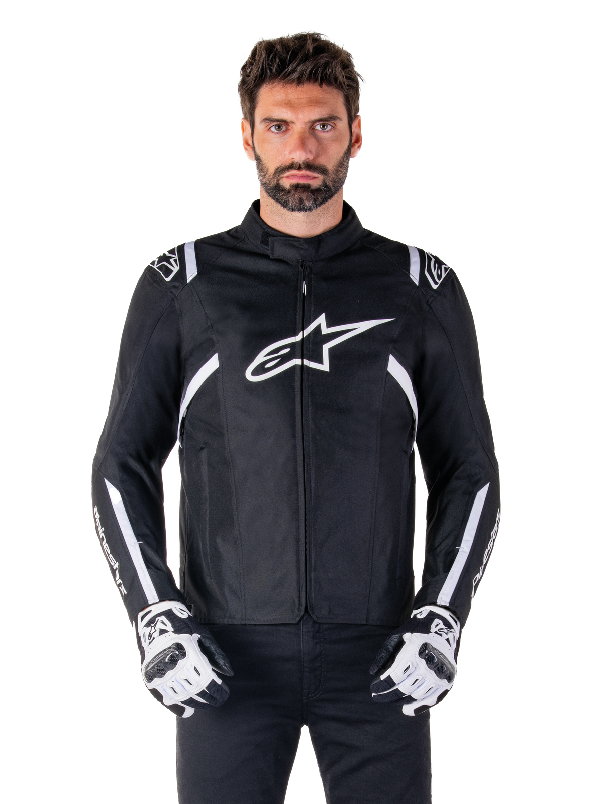 Giacca Alpinestars T-SPS V2 Waterproof in nero e bianco, vista frontale su modello, giacca da moto impermeabile in tessuto con strisce bianche su spalle e braccia, grande logo Alpinestars bianco sul petto, indossata con guanti protettivi da moto, silhouette sportiva ed elegante
