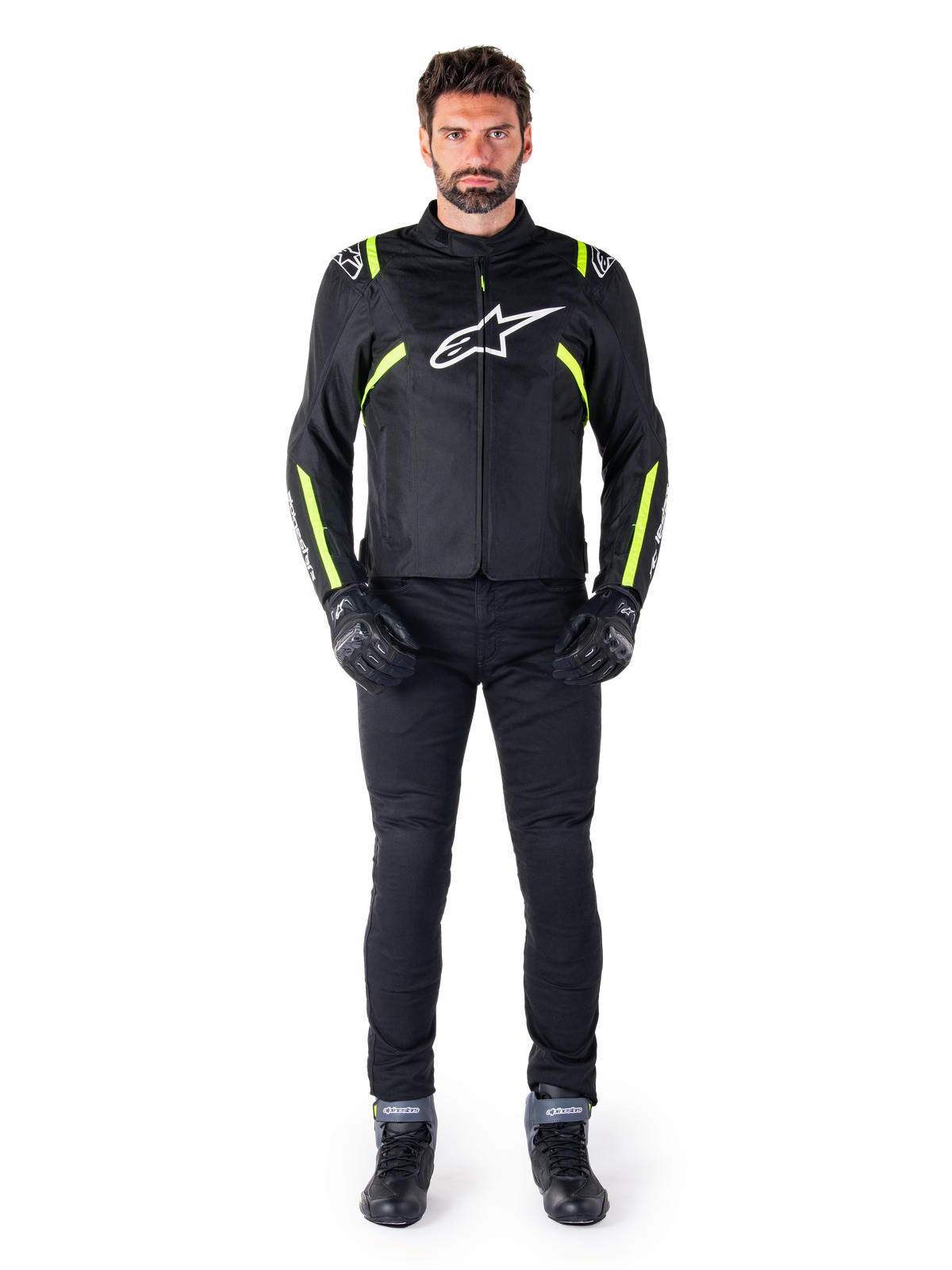 Giacca impermeabile Alpinestars T-SPS V2, nero, bianco e giallo fluo, indossata da un modello con pantaloni e guanti da moto neri, con logo Alpinestars bianco sul petto e dettagli fluorescenti su spalle e maniche, abbigliamento da moto dal taglio sportivo
