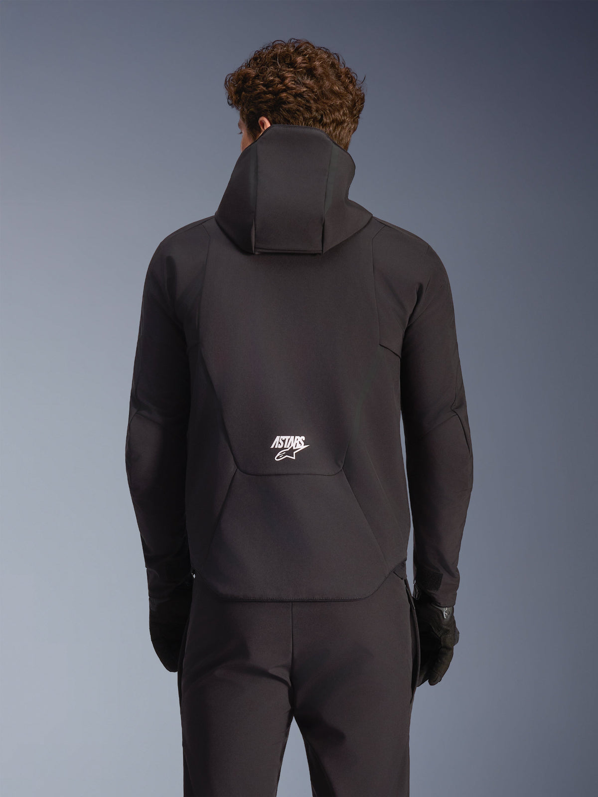 Alpinestars Giacca Aeroshell Impermeabile, giacca moto softshell da uomo, nera, vista posteriore con cappuccio e logo bianco