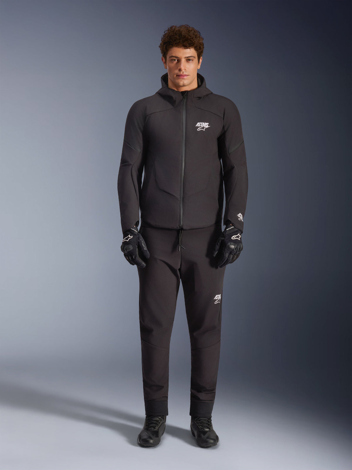 Alpinestars Giacca Aeroshell Impermeabile, giacca da moto nera in softshell con cappuccio, indossata da un modello.