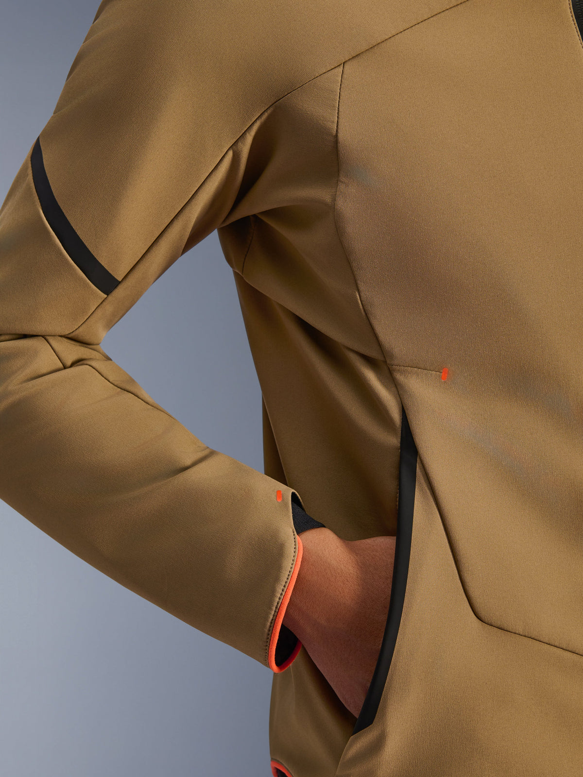 Primo piano della giacca Alpinestars Aeroshell Waterproof, Dark Khaki con accenti neri e arancione fluo, dettaglio della tasca nascosta con zip e del polsino, tessuto softshell elasticizzato per la guida in moto
