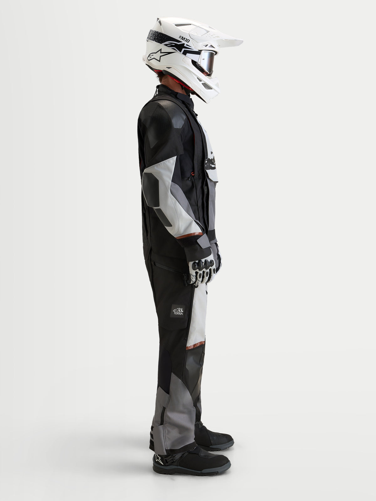 Alpinestars Harok V 2 Giacca Drystar, giacca da moto all-terrain adventure da uomo, grigio scuro, grigio ghiaccio e nero, indossata con casco bianco e abbigliamento da adventure riding, vista laterale in studio
