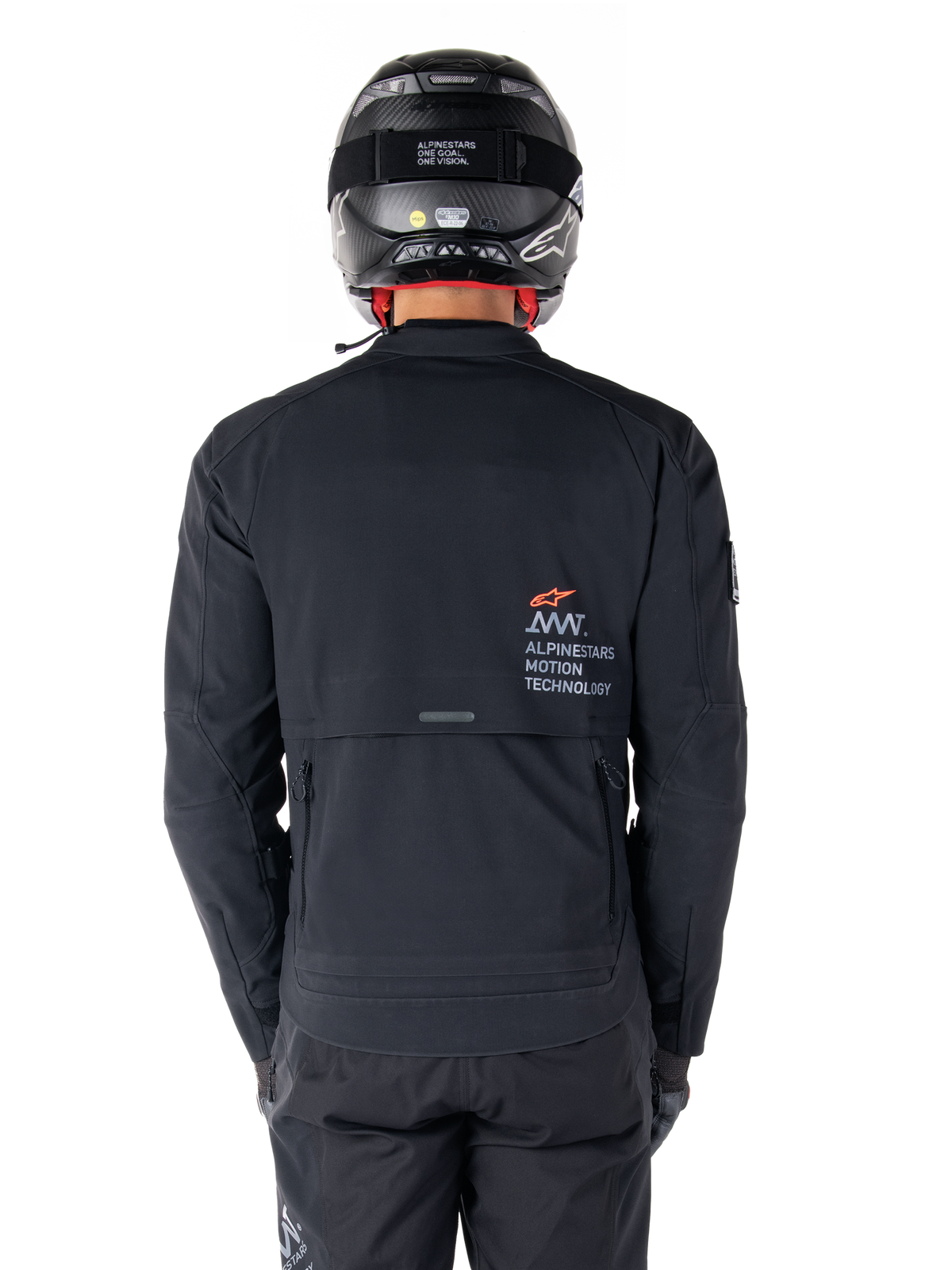 Giacca Alpinestars AMT-8 Stretch Drystar® XF, vista posteriore, nera, indossata con casco e pantaloni neri, con marchio Alpinestars Motion Technology sul retro, design adventure touring in materiale elasticizzato ergonomico.