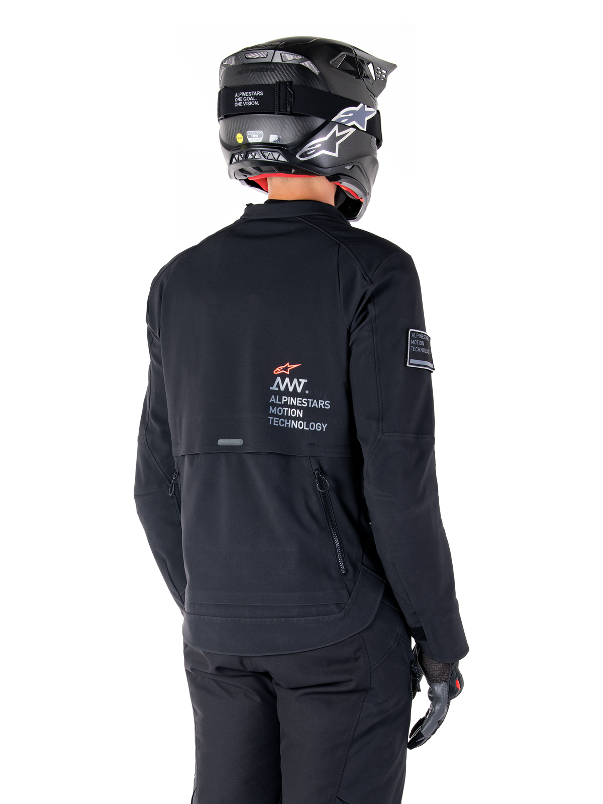 Vista posteriore di un pilota che indossa la giacca Alpinestars AMT-8 Stretch Drystar® XF in nero, caratterizzata dal marchio 'AMT Alpinestars Motion Technology' sulla schiena e ventilazione tecnica con cerniera, abbinata a casco da moto e guanti neri