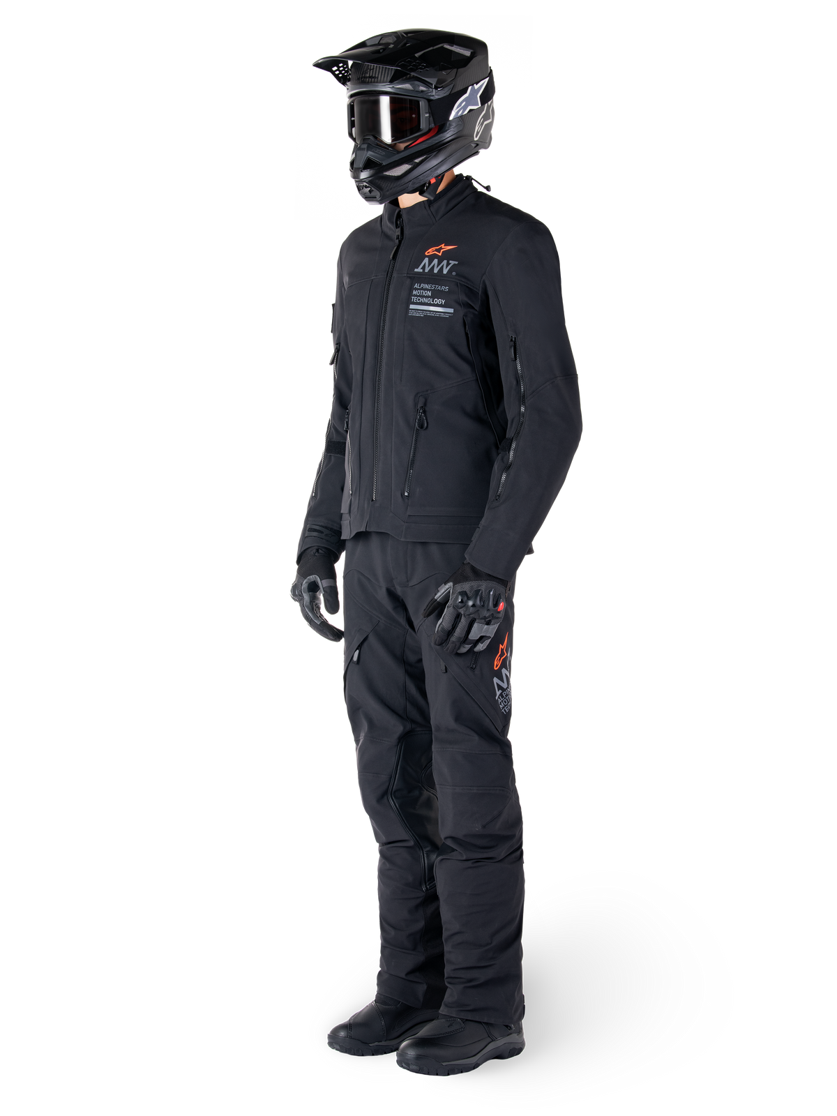 Alpinestars AMT-8 Stretch Drystar® XF Jacket, giacca da moto adventure, nero, indossata con pantaloni coordinati, casco e guanti, con marchio Alpinestars Motion Technology e accenti arancioni, struttura elasticizzata resistente per la guida adventure