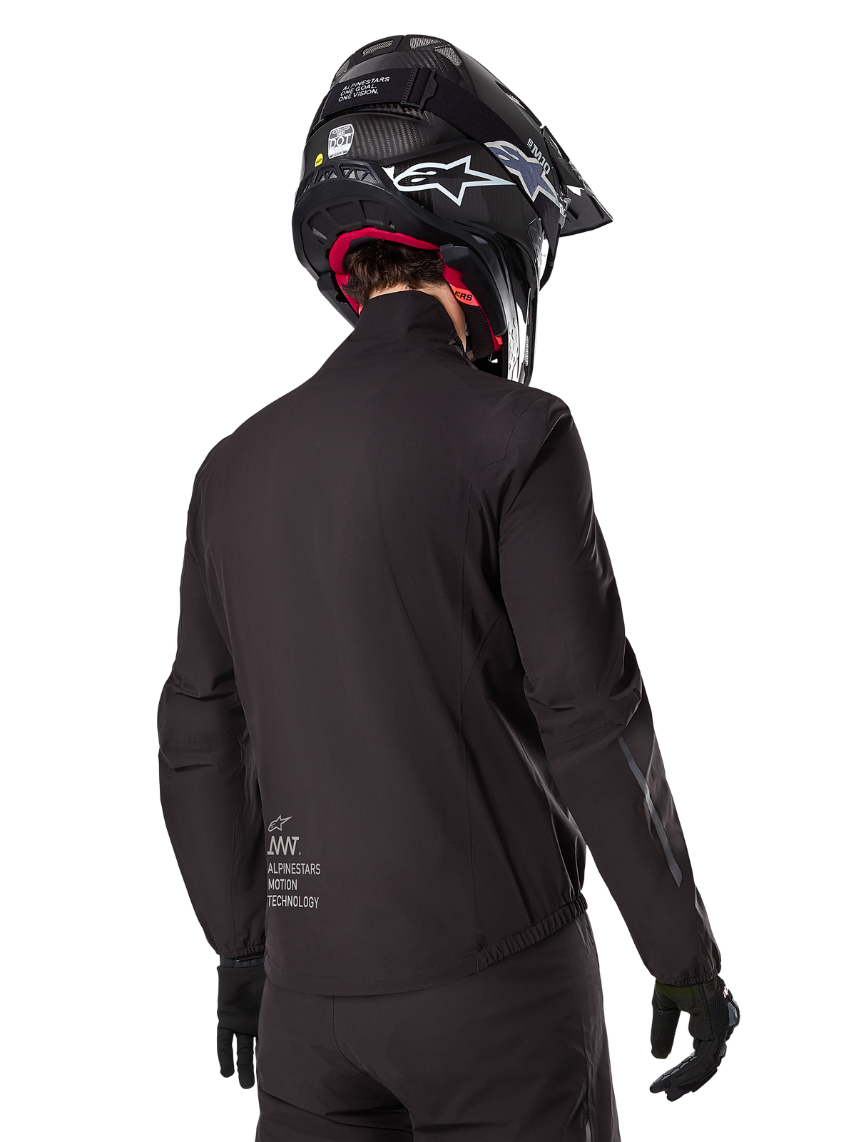 Alpinestars AMT-8 Stretch Drystar® XF Liner, fodera per giacca impermeabile nera, vista posteriore di un pilota che indossa un casco e guanti neri, logo Alpinestars Motion Technology sulla parte bassa della schiena, design minimalista e funzionale per la guida adventure