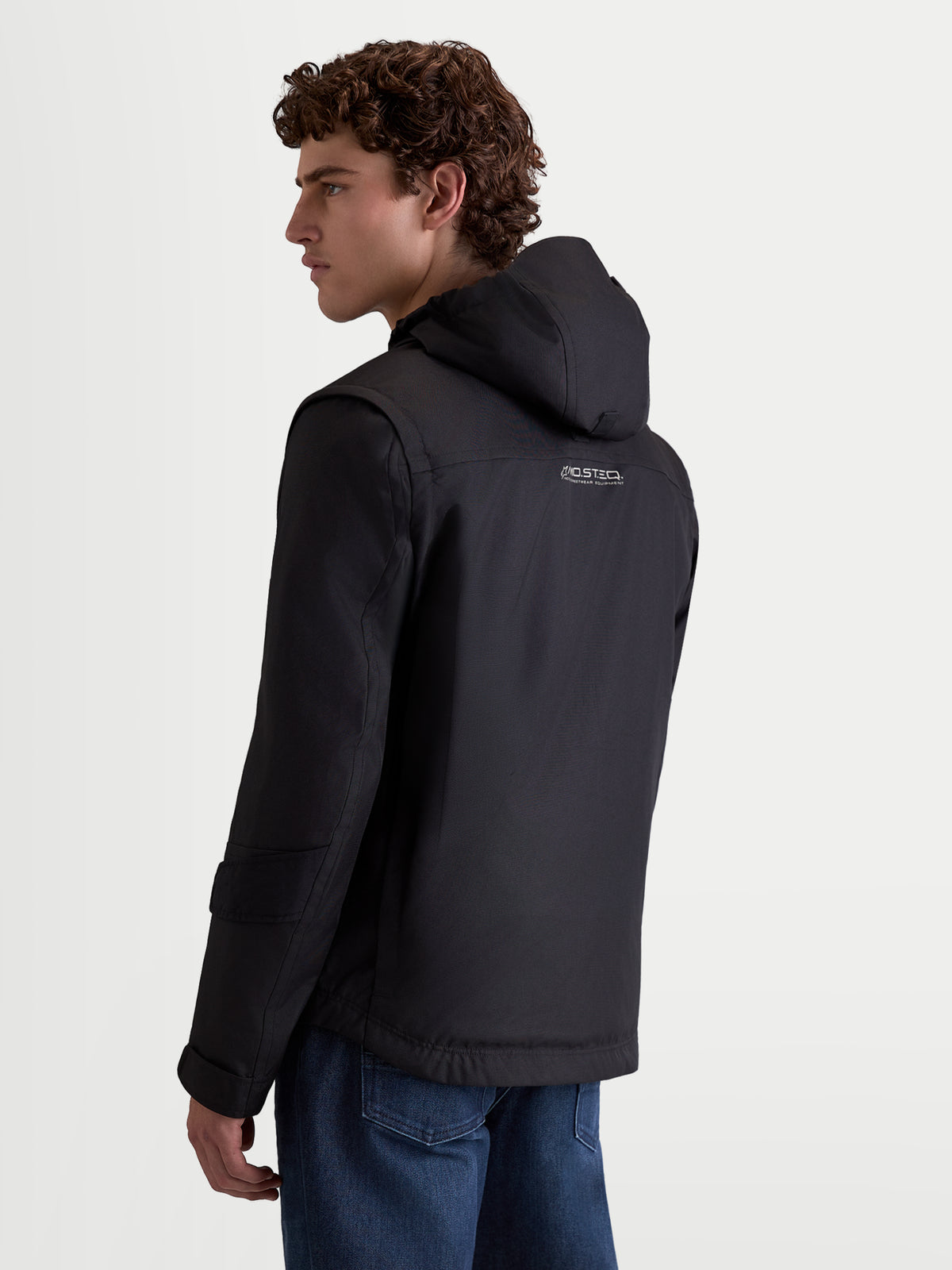 Alpinestars Morfex Parka Wp Jkt, giacca da moto urbana contemporanea da uomo, colore nero, vista posteriore a tre quarti su un modello che indossa la giacca in tessuto con cappuccio integrato