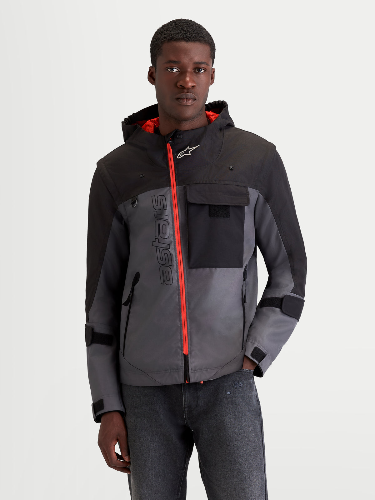 Alpinestars Morfex Parka WP Giacca, giacca da moto urbana contemporanea da uomo in grigio lunare e nero, vista frontale su un modello che indossa la giacca da moto modulare in tessuto con zip frontale arancione a contrasto e cappuccio integrato