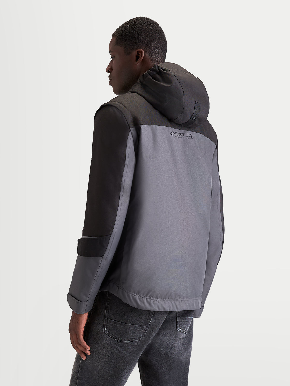 Alpinestars Morfex Parka Wp Giacca, giacca da moto urbana contemporanea da uomo, grigio chiaro e nero, vista posteriore di tre quarti con cappuccio integrato e struttura in tessuto impermeabile indossata da un modello