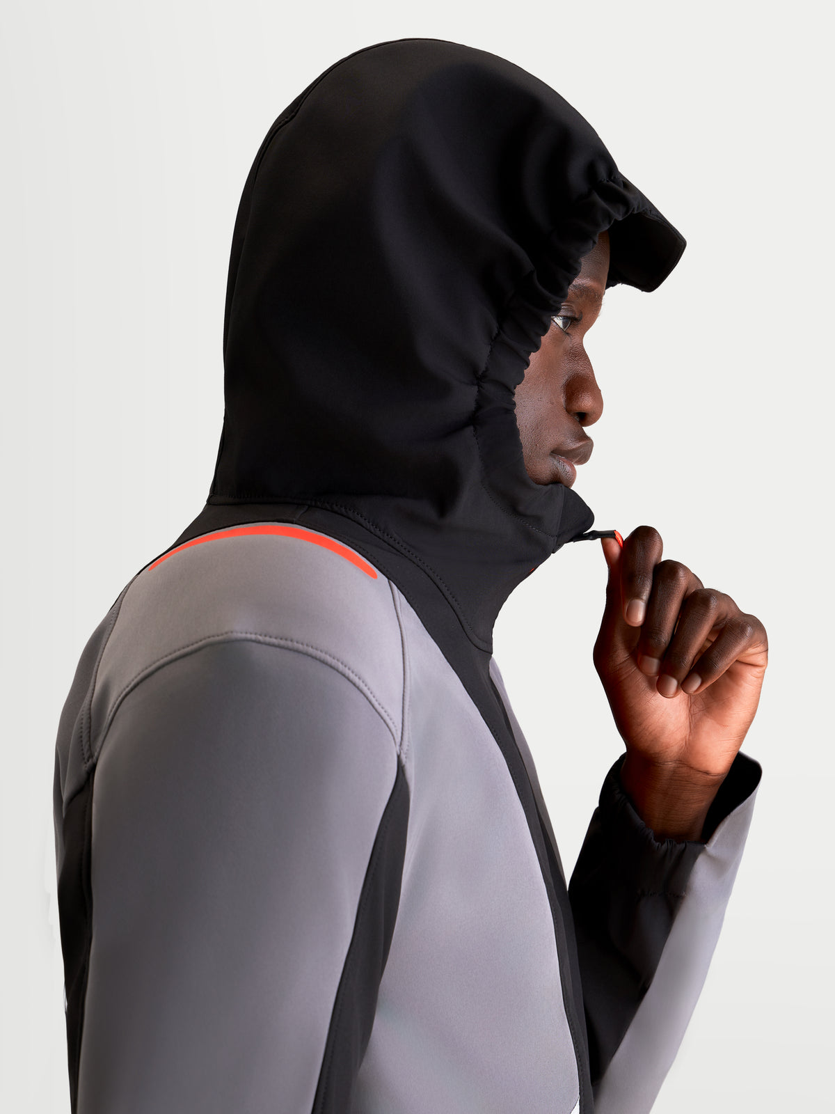 Alpinestars C 5 Drystar Giacca, giacca da moto urbana contemporanea da uomo in nero e grigio scuro, vista di profilo laterale di un modello che indossa la giacca impermeabile con il cappuccio integrato sollevato mentre regola la cerniera anteriore