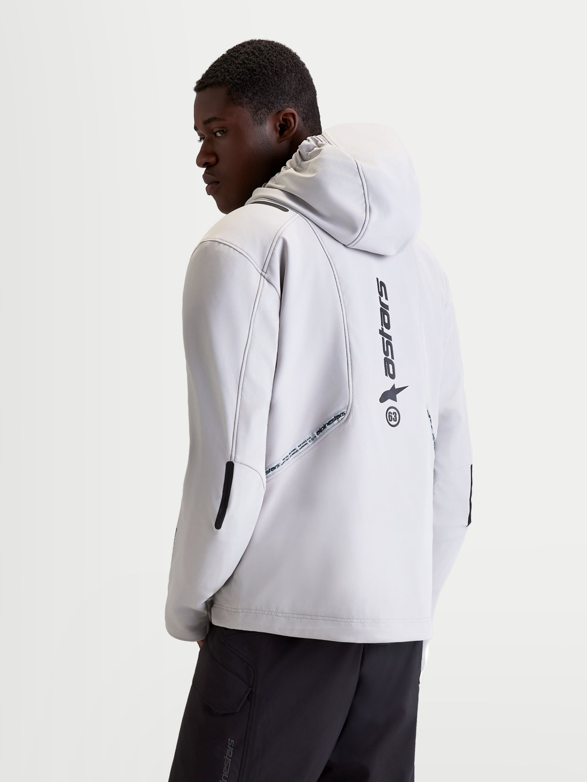 Alpinestars C 5 Drystar Giacca, giacca da moto urbana contemporanea da uomo in grigio chiaro e nero, vista posteriore su un modello che mostra il cappuccio integrato, la struttura softshell e i dettagli del logo verticale sul retro