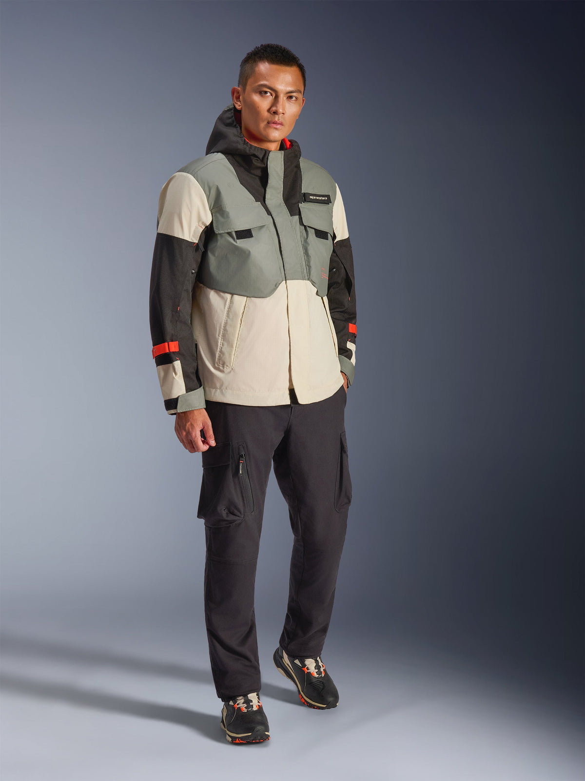 Giacca Alpinestars Mospher Waterproof in Fur Gray Black Ice, parka tecnico da moto multicolore con pannelli grigi, neri e bianco sporco e accenti rossi, design funzionale con ampie tasche e cappuccio, indossata con pantaloni cargo grigio scuro e sneakers nere, abbigliamento da moto urban contemporary