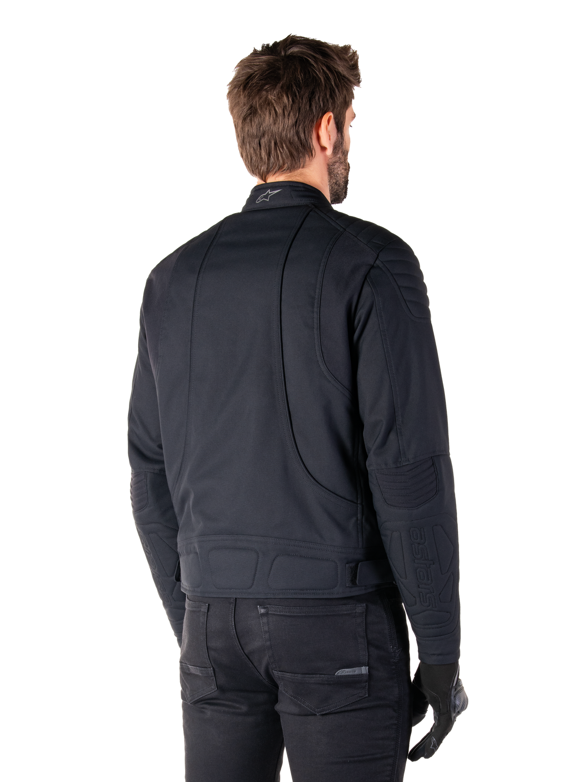 Giacca Alpinestars Clayton WR in nero, vista posteriore di tre quarti su un modello maschile, giacca da moto urbana con imbottitura trapuntata su spalle e gomiti, linee di cucitura tecniche e logo riflettente sul colletto, abbinata a pantaloni e guanti neri.