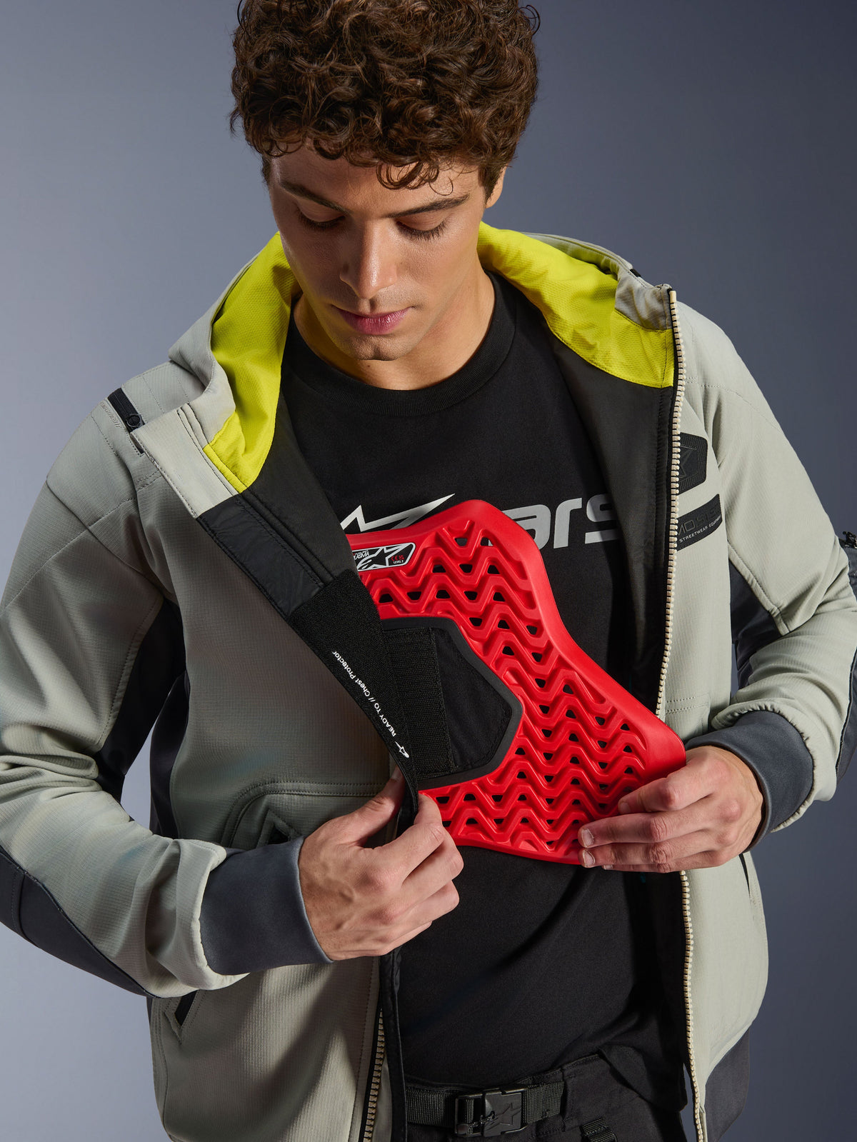 Giacca impermeabile Alpinestars Moblast WP, Iron Gray e Dark Sage, modello che mostra l'integrazione della protezione toracica con un inserto protettivo rosso, fodera interna verde lime vivace, abbigliamento moderno da moto per uso urbano