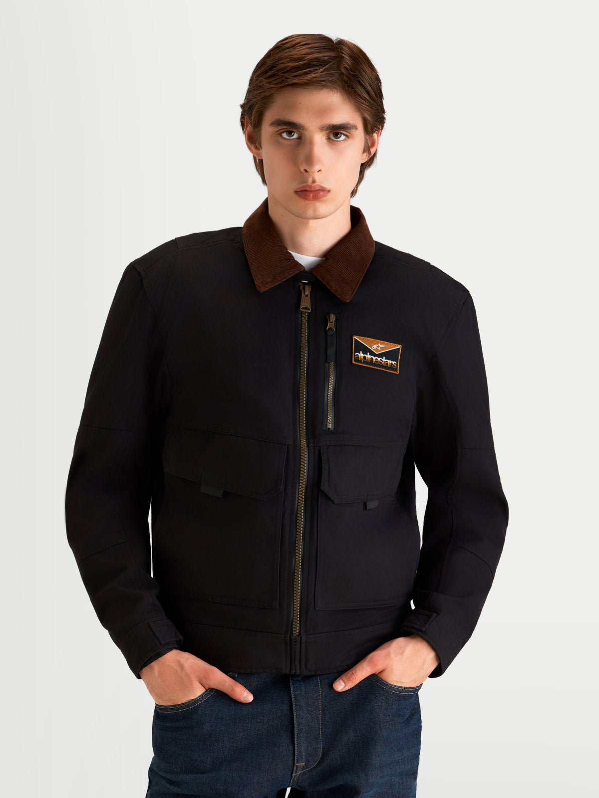 Alpinestars Mustang Waterproof Giacca da moto, giacca da moto urbana da uomo in antracite scuro e marrone scuro, vista frontale su un modello che indossa abbigliamento da guida in stile workwear con collo a coste a contrasto