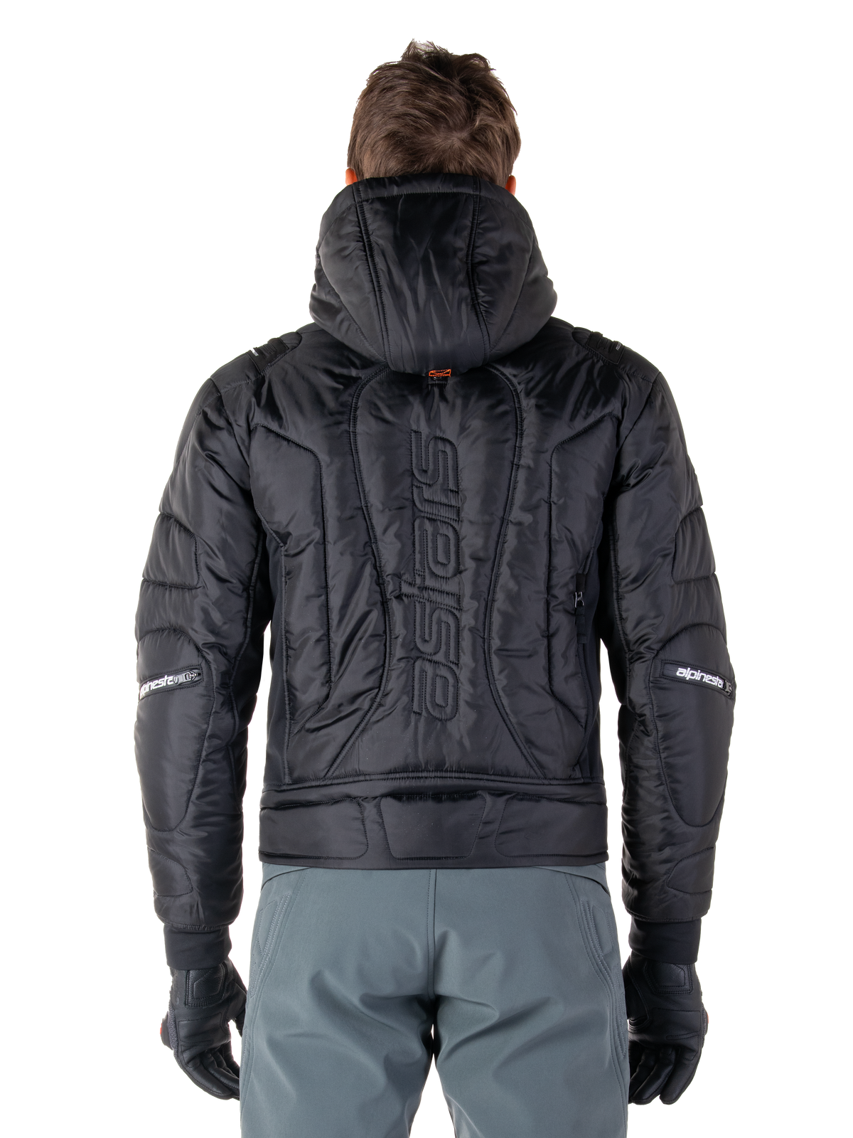 Giacca Alpinestars Mohobbs Waterproof, nero, vista posteriore che mostra la costruzione imbottita e trapuntata, marchio 'astars' verticale sul retro, cappuccio alzato, stile streetwear motociclistico contemporaneo