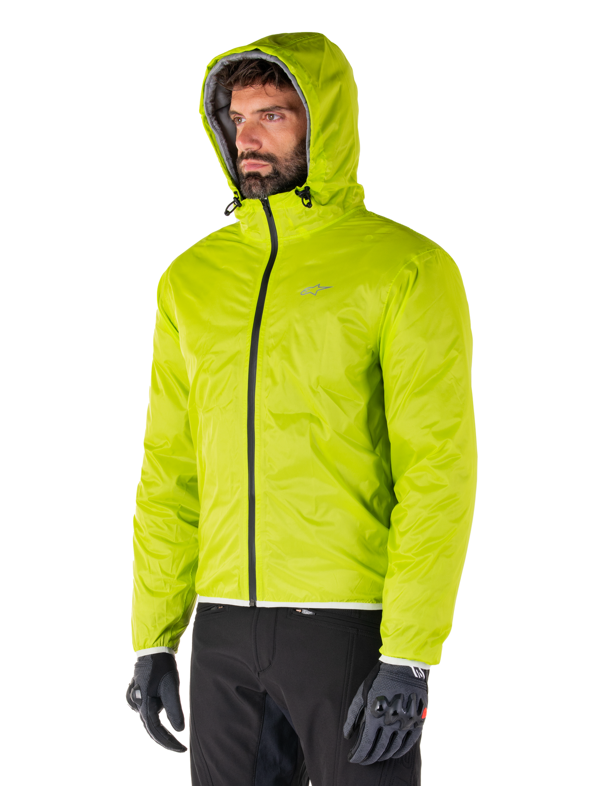 Giacca impermeabile Alpinestars Mohobbs, fodera antipioggia ripiegabile Lime Punch, giacca con cappuccio verde neon brillante indossata con pantaloni neri e guanti grigi, abbigliamento da moto ispirato allo streetwear urbano