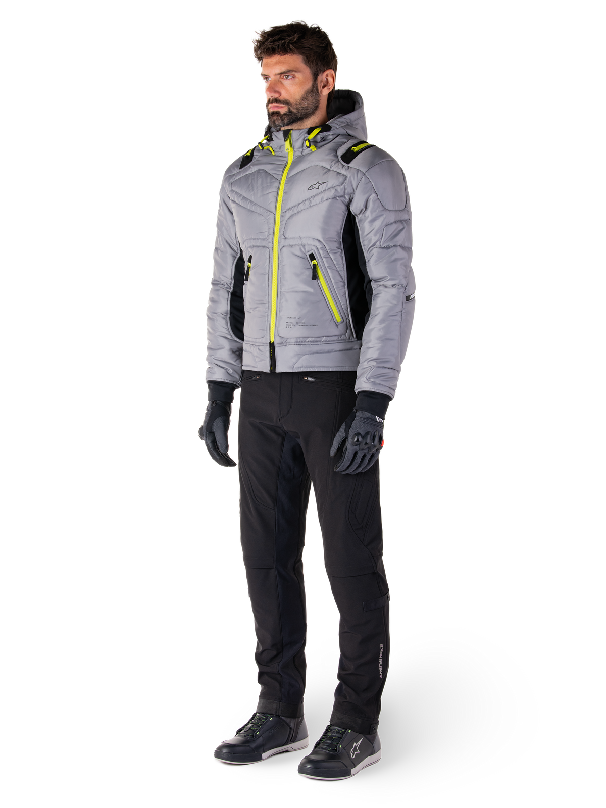Giacca Alpinestars Mohobbs Waterproof in Lunar Gray e Lime Punch, giacca da moto trapuntata stile bomber con accenti neon, indossata da un modello con pantaloni da guida e guanti neri, abbigliamento protettivo ispirato allo streetwear urbano