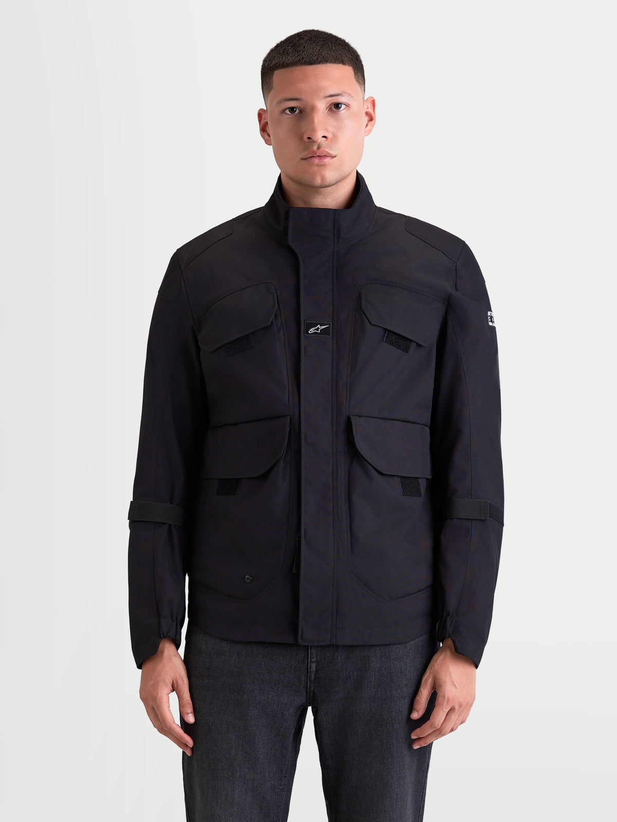 Alpinestars Altan Drystar Giacca, giacca da moto urbana contemporanea da uomo, colore nero, vista frontale su un modello che mostra la struttura in tessuto polyfabric, le tasche cargo a doppio accesso e il colletto ergonomico
