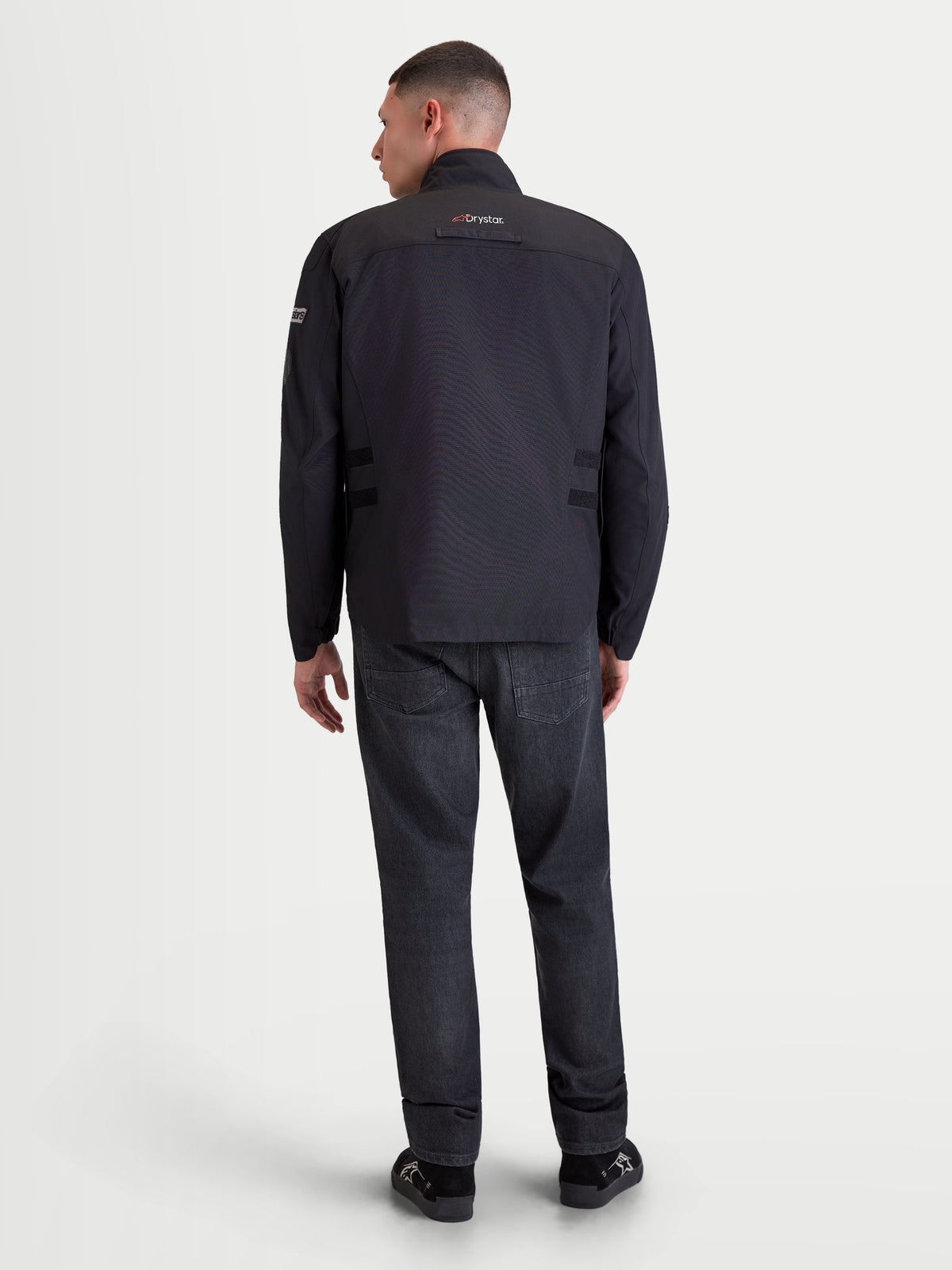Alpinestars Altan Drystar Giacca, giacca da moto urban contemporary da uomo in colore nero, vista posteriore su un modello che mostra la costruzione impermeabile, il colletto caldo integrato e il marchio Drystar
