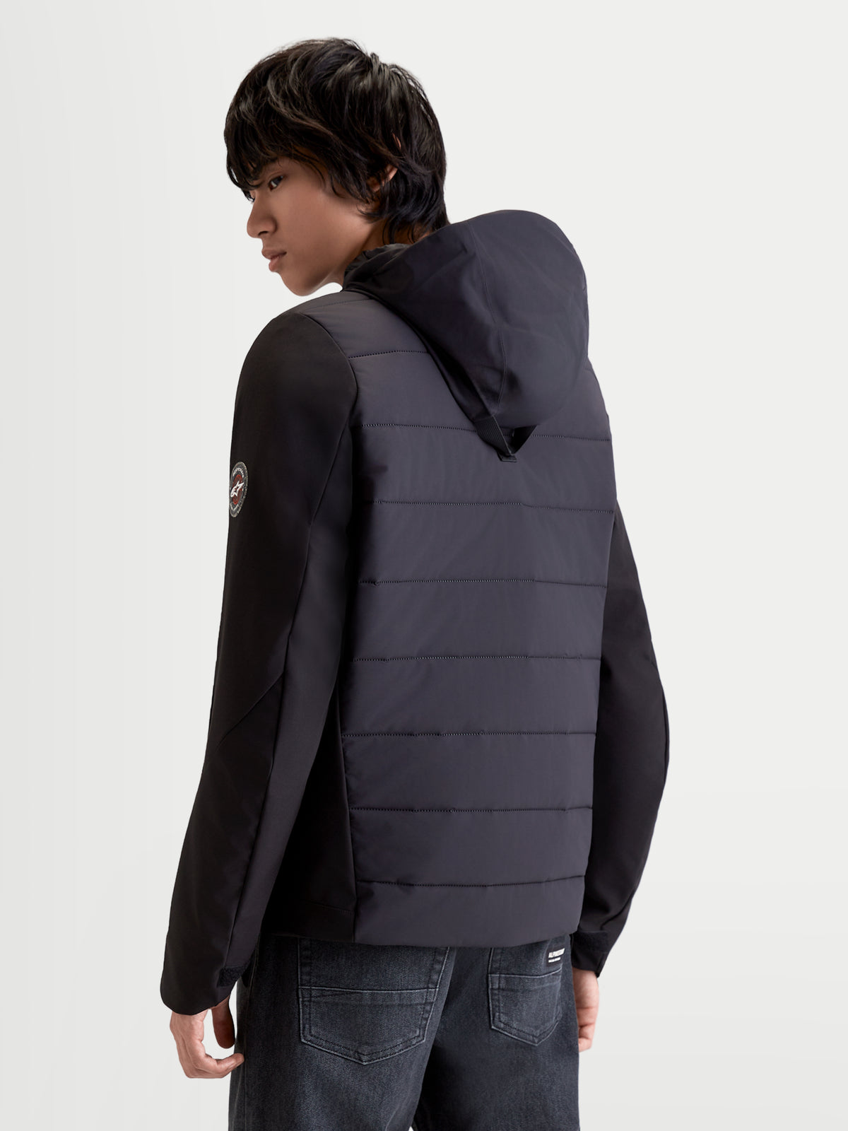 Alpinestars Therma Tech WP Giacca, giacca da moto urban da uomo, colore nero, vista posteriore tre quarti che mostra la struttura trapuntata e il sistema di cappuccio integrato indossata da un modello