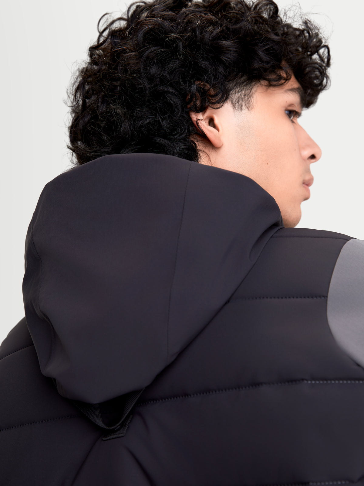 Alpinestars Therma-Tech Waterproof Jacket, giacca da moto urbana da uomo in nero e grigio scuro, primo piano della vista posteriore che mostra il sistema di cappuccio integrato e la struttura termosaldata indossata da un modello