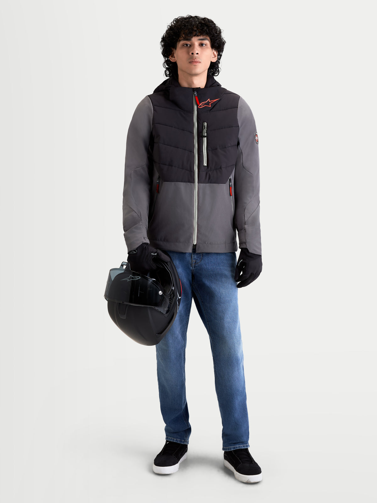 Alpinestars Giacca Therma-Tech Impermeabile, giacca da moto urbana contemporanea da uomo in nero e grigio scuro, vista frontale su un modello che indossa jeans, guanti e tiene un casco