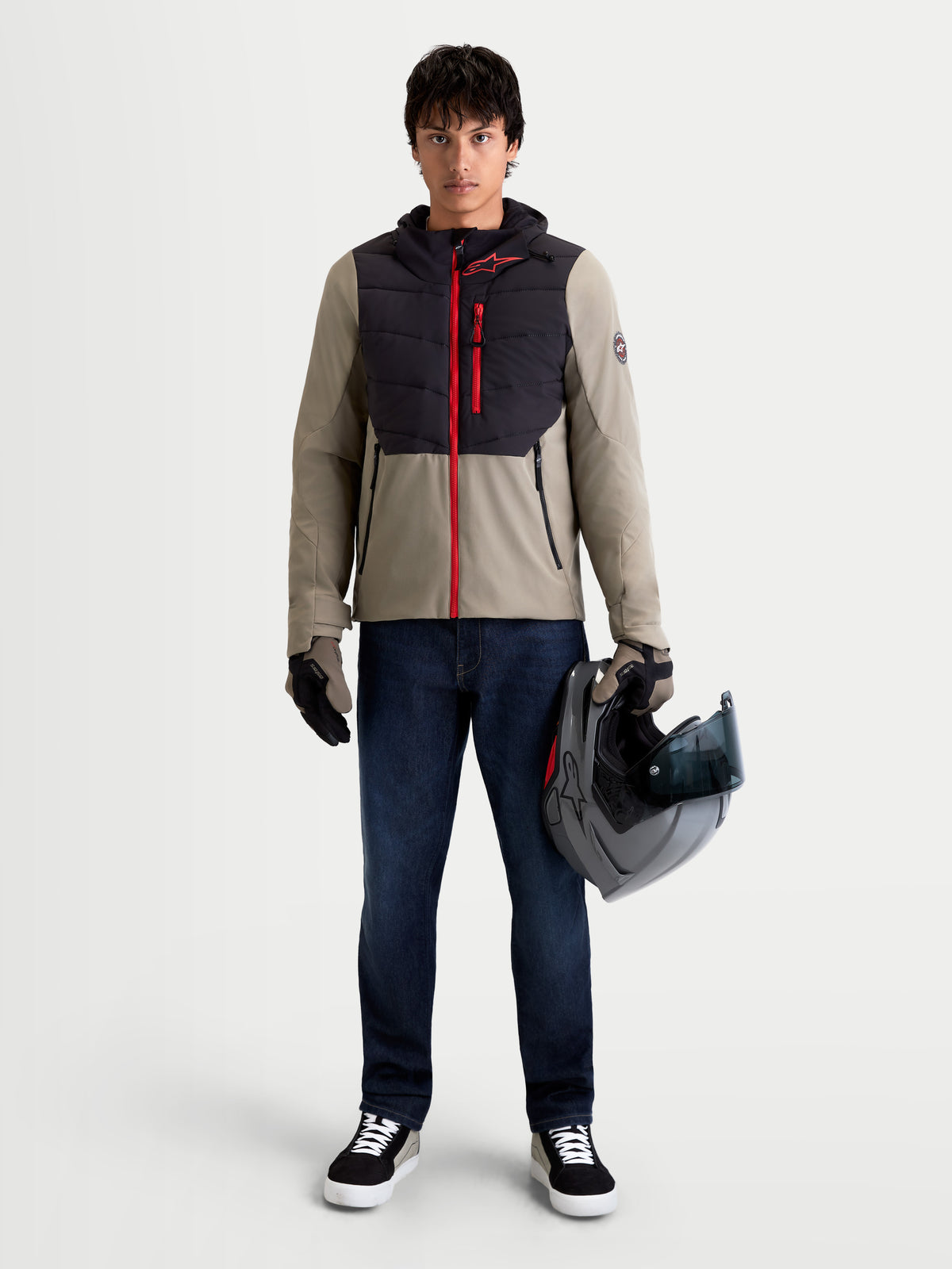 Alpinestars Therma-Tech Giacca impermeabile, giacca da moto urbana contemporanea da uomo in nero e vetiver, vista frontale su un modello che indossa guanti coordinati e tiene un casco, abbigliamento da strada impermeabile e termico