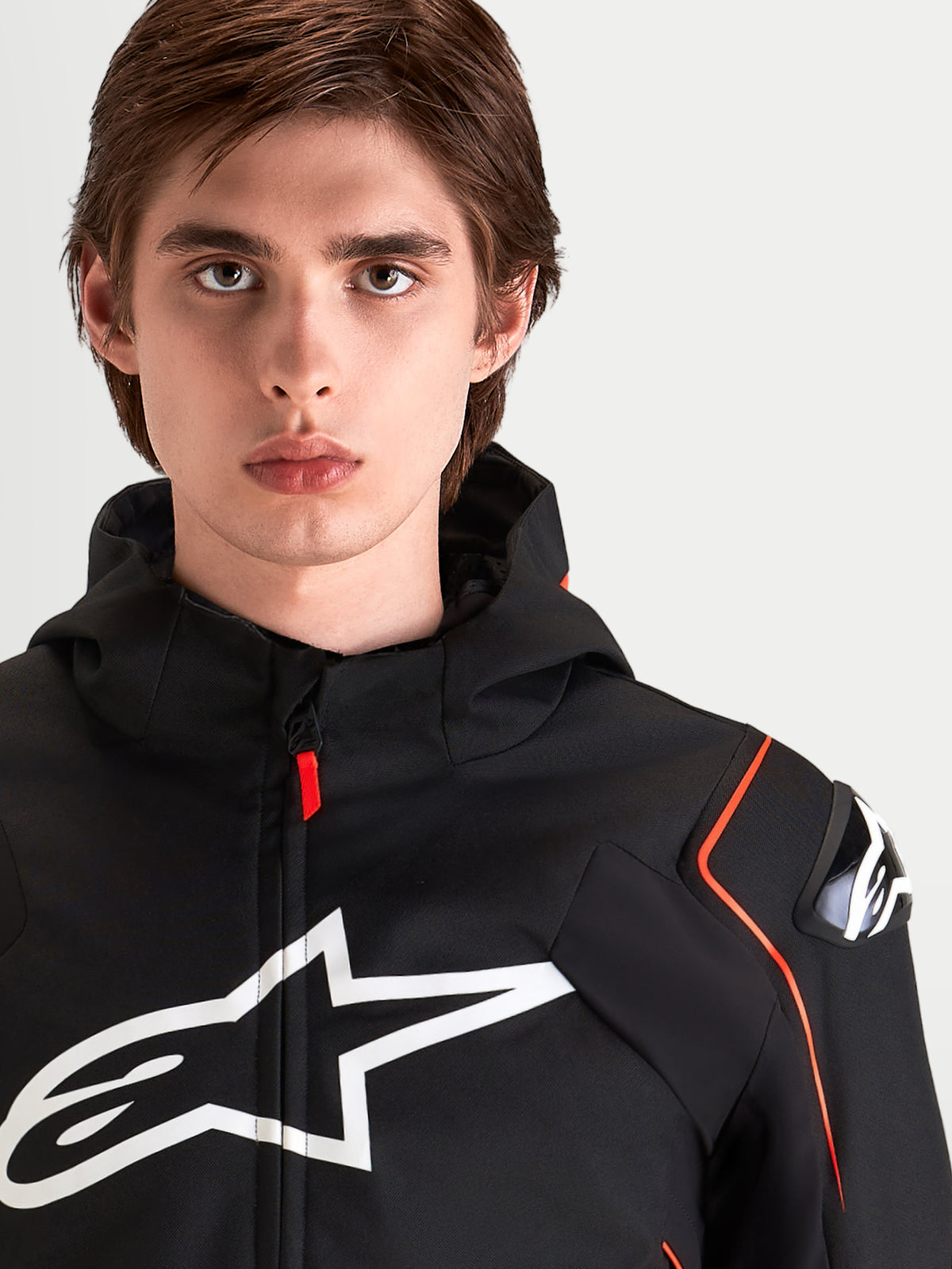 Alpinestars Zaca V 2 Waterproof Giacca, giacca da moto sportiva da uomo, nero e rosso fluo, con protezioni spalle DFS e grande logo sul petto, ritratto in primo piano di un pilota