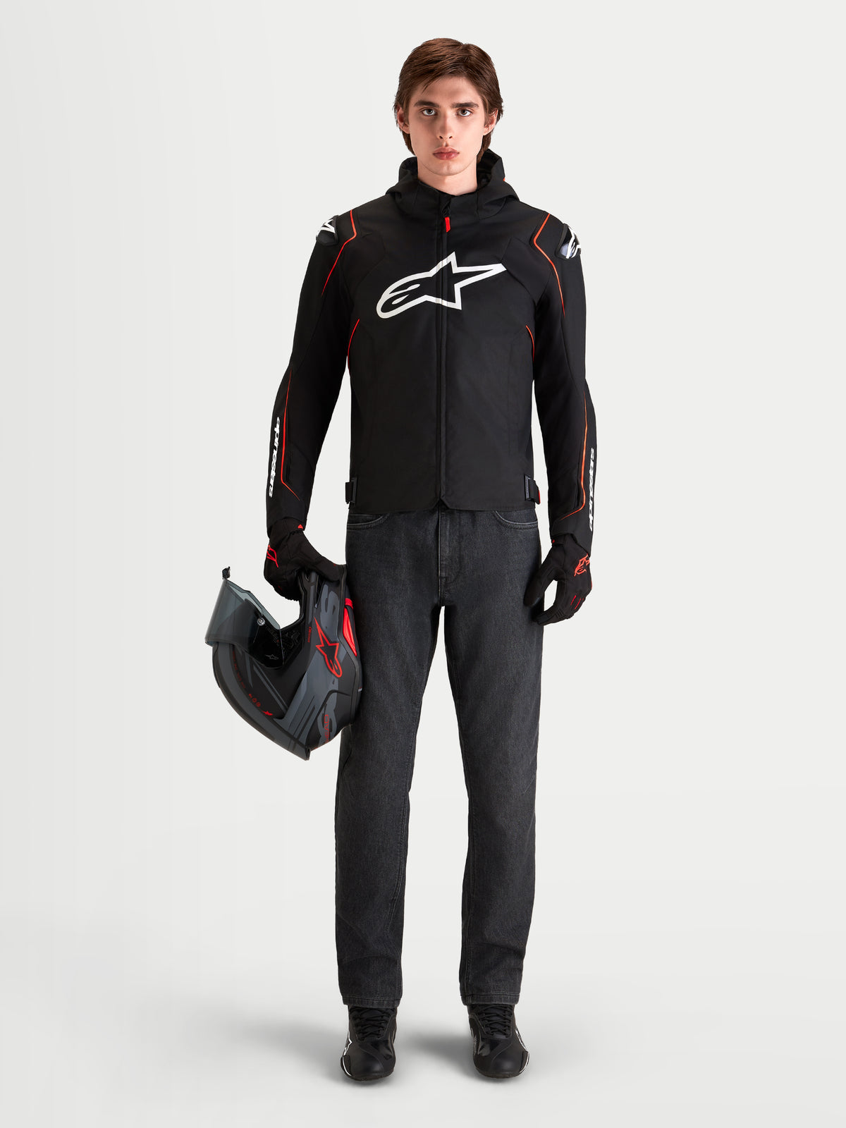 Alpinestars Zaca V 2 Waterproof Giacca, giacca da moto sportiva da uomo con protezioni spalle DFS e cappuccio integrato, nero e rosso fluo, indossata da un modello che tiene un casco