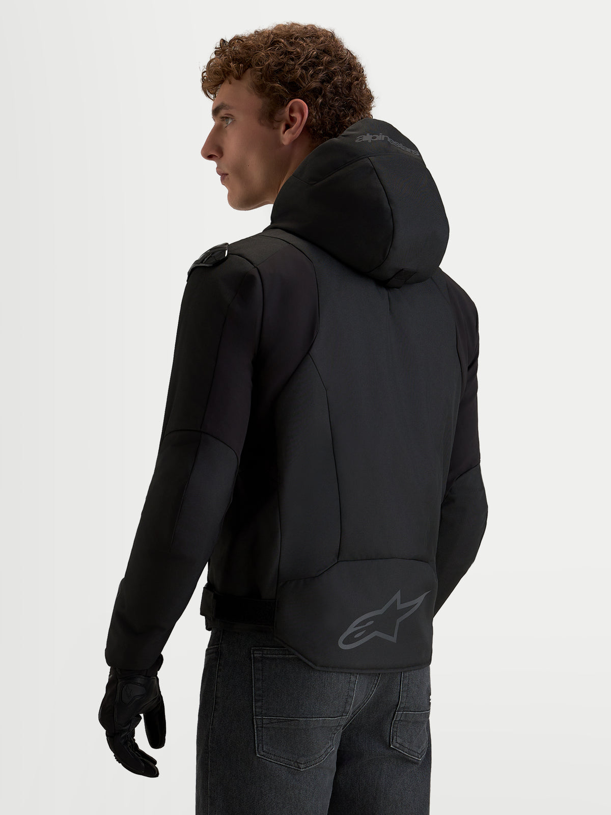 Alpinestars Zaca V2 Waterproof Giacca, giacca da moto impermeabile da uomo con cappuccio integrato e logo posteriore, nera, indossata da un modello, vista posteriore