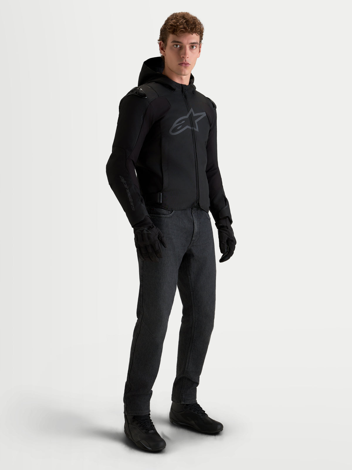 Alpinestars Zaca V 2 Waterproof Giacca, giacca da moto impermeabile da uomo con cappuccio, nera, indossata da un modello con pantaloni scuri