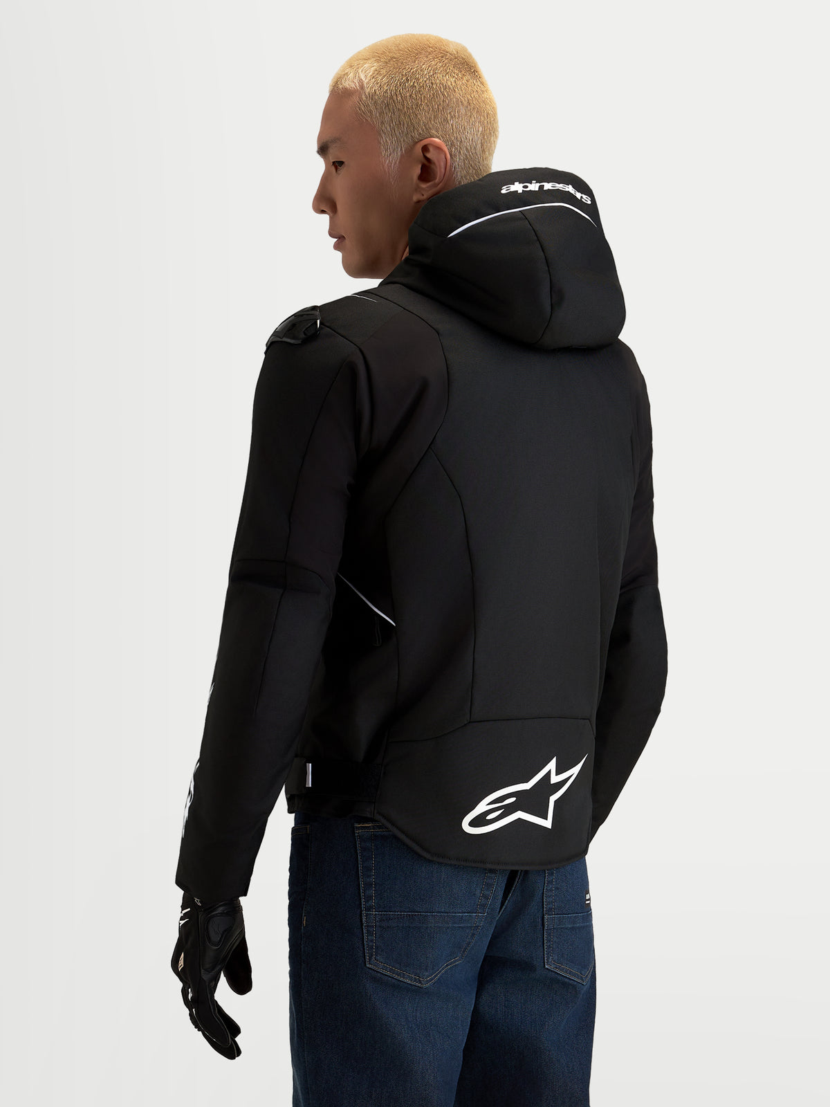 Alpinestars Zaca V 2 Waterproof Giacca, giacca da moto impermeabile da uomo, nero e bianco, vista posteriore con cappuccio integrato con logo Alpinestars bianco, orlo posteriore allungato con grande logo a stella e dettagli di protezione sulle spalle