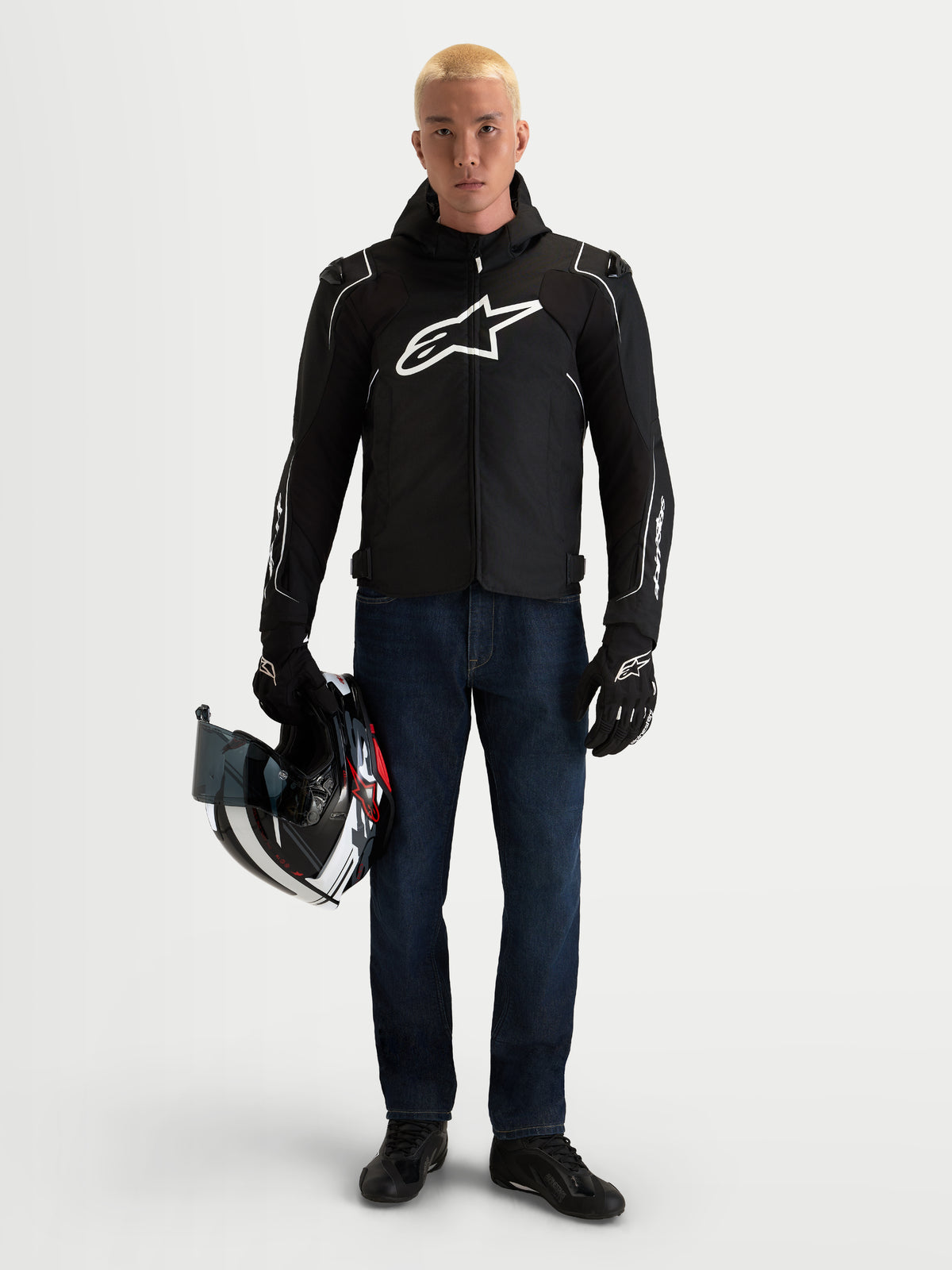 Alpinestars Zaca V 2 Waterproof Giacca, giacca da moto in tessuto impermeabile con cappuccio integrato, da uomo, nero e bianco, indossata da un modello che tiene un casco