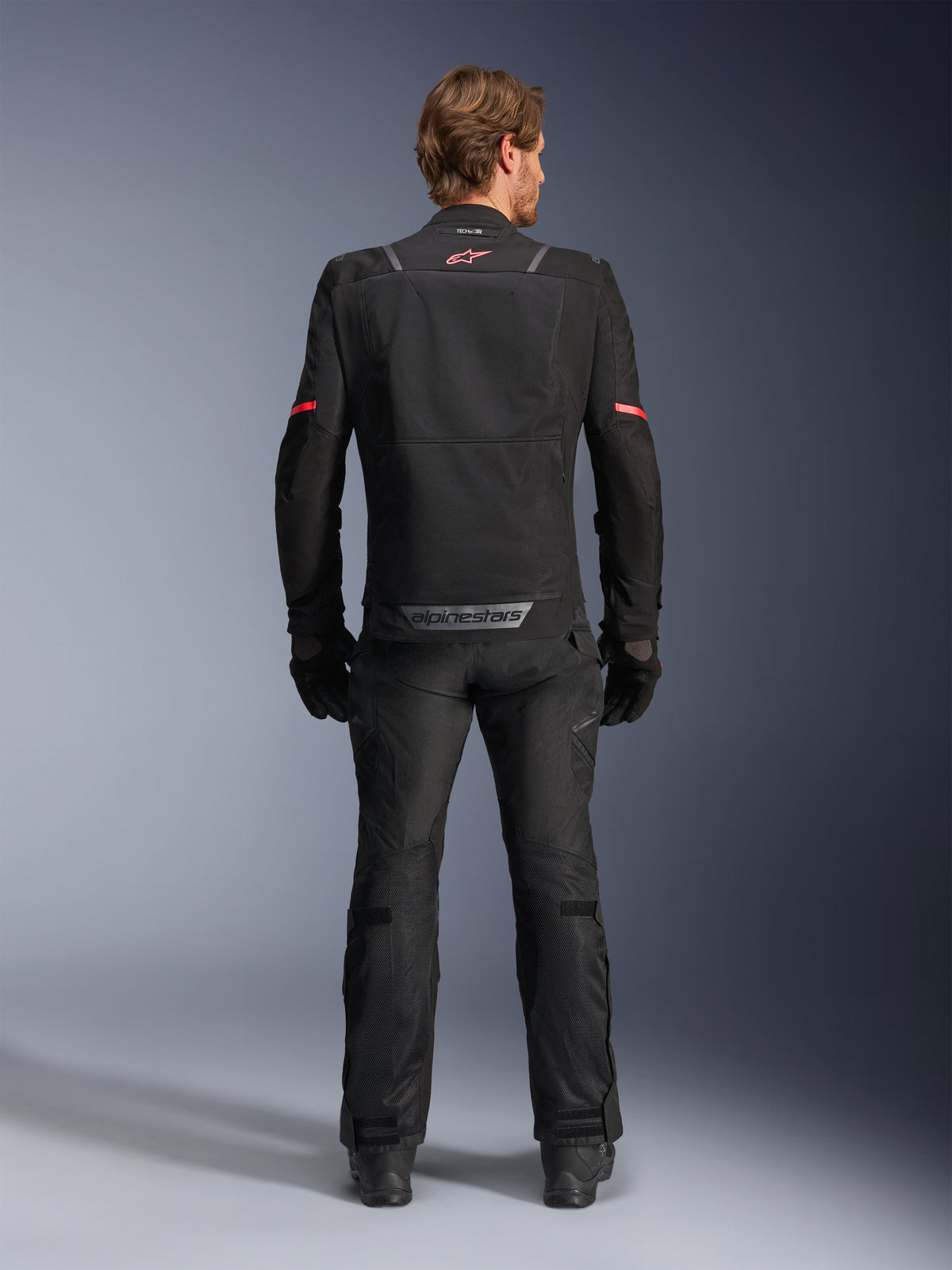 Alpinestars Giacca ST-2 Air, giacca da moto touring da uomo, nera, vista posteriore con pannelli in mesh, logo rosso e marchio grigio sul bordo inferiore
