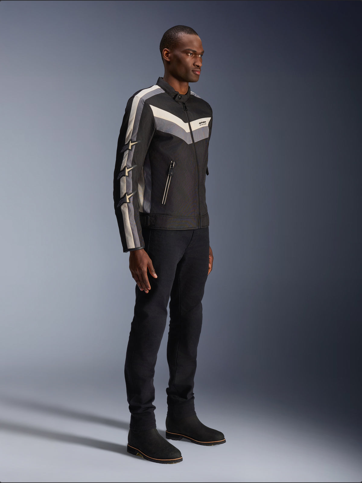 Giacca Alpinestars T-Dyno WR, giacca da moto in tessuto, nera con dettagli a gallone grigio scuro ed ecru, vestibilità biker d'ispirazione vintage, indossata con pantaloni e stivali neri per un look da strada completo