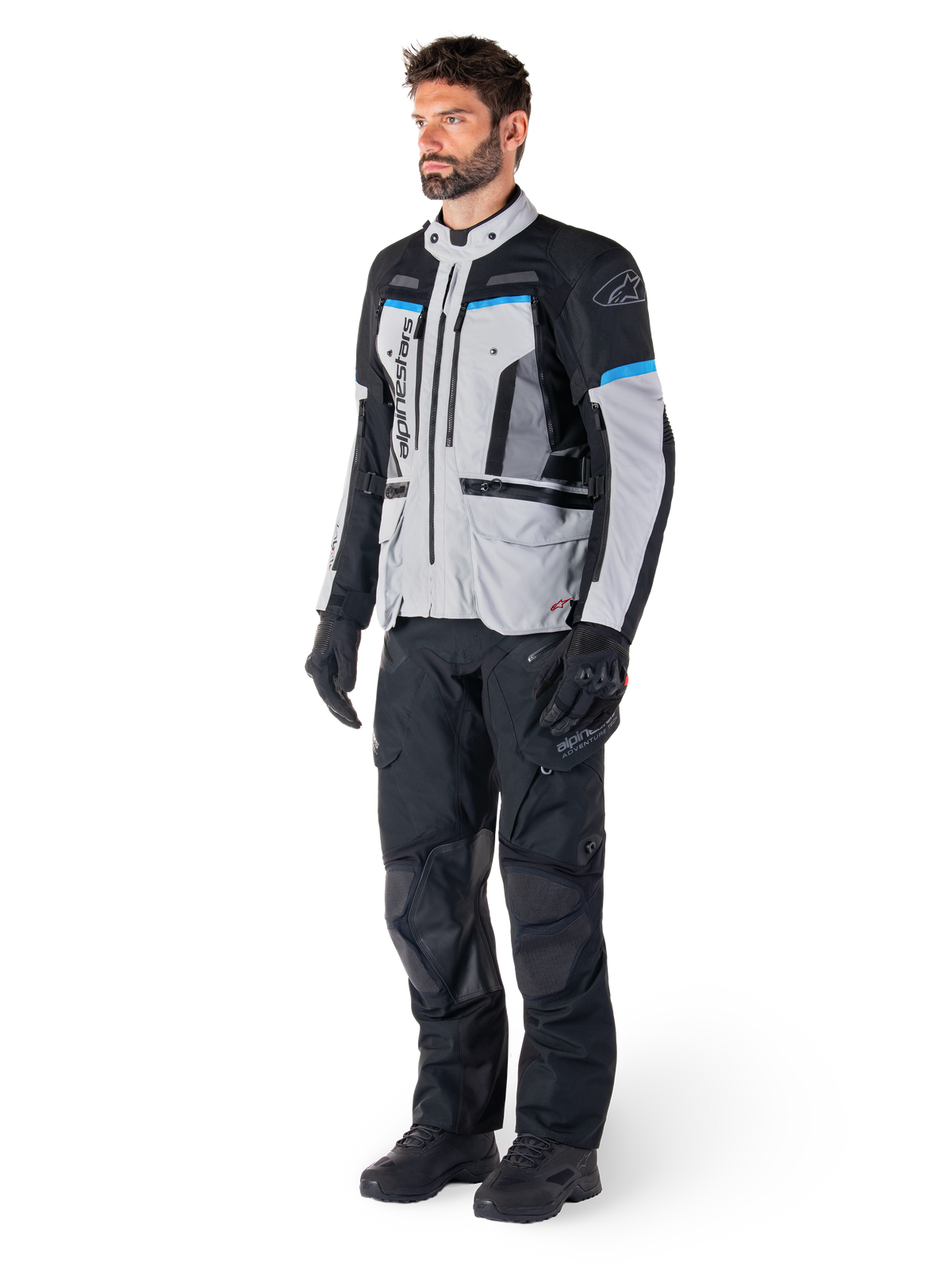 Alpinestars Giacca Bogotá Pro Drystar®, giacca da moto adventure touring da uomo, grigio ghiaccio, nero e ciano, impermeabile, Tech-Air® Ready, certificata CE, indossata con pantaloni e guanti neri.