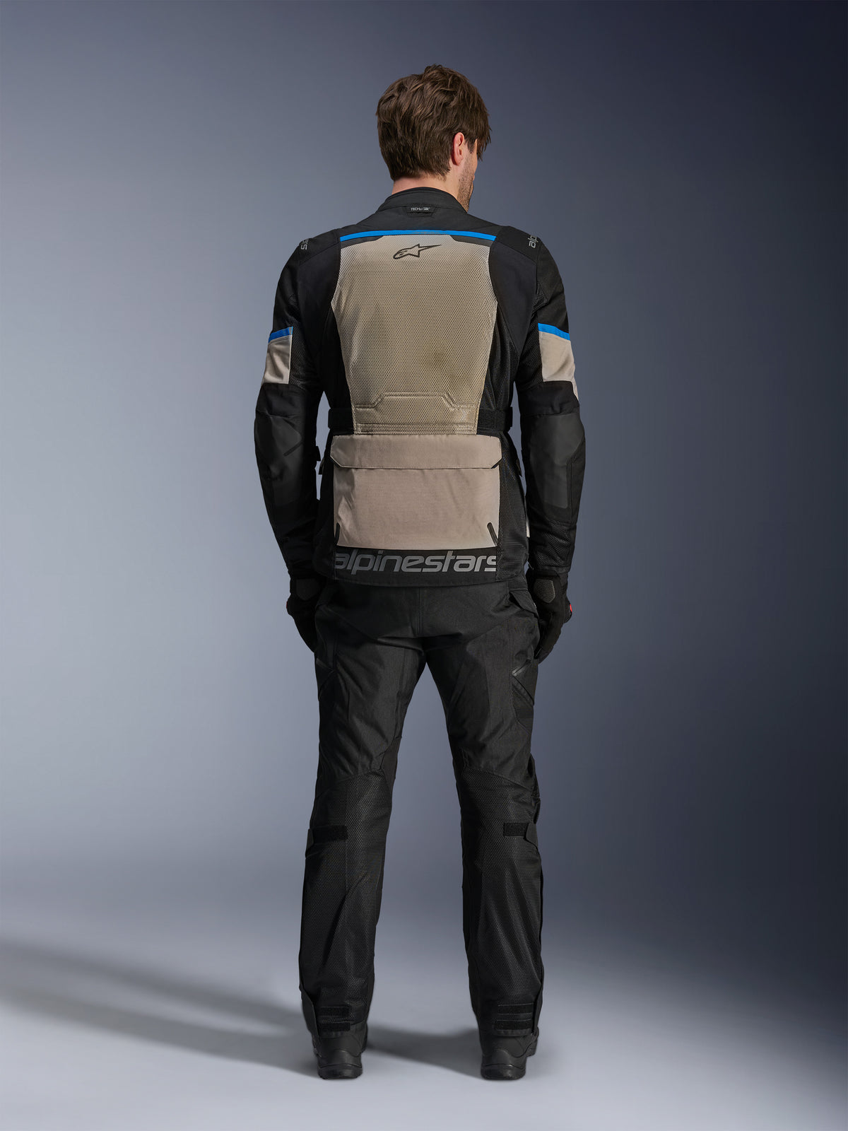 Giacca Alpinestars Andes Air Drystar®, Black Laurel Gray Bright Blue, vista posteriore con ampio pannello di ventilazione in rete, grande tasca portaoggetti posteriore con marchio Alpinestars, giacca tecnica da mototurismo indossata con pantaloni abbinati