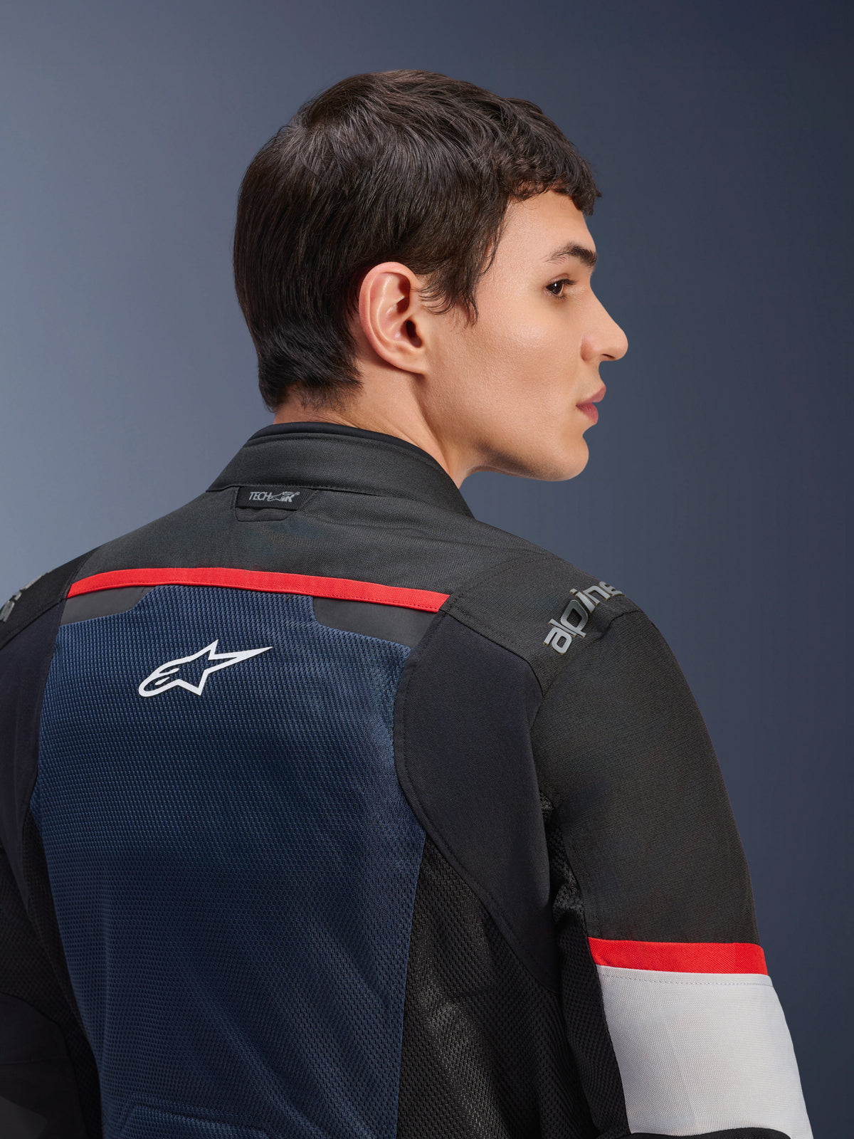Giacca Alpinestars Andes Air Drystar®, blu scuro, nero e grigio ghiaccio, vista posteriore ravvicinata su un modello, con pannello in rete traspirante, logo a stella bianco, accenti rossi e marchio Tech-Air® sul colletto, abbigliamento da moto da turismo per due stagioni