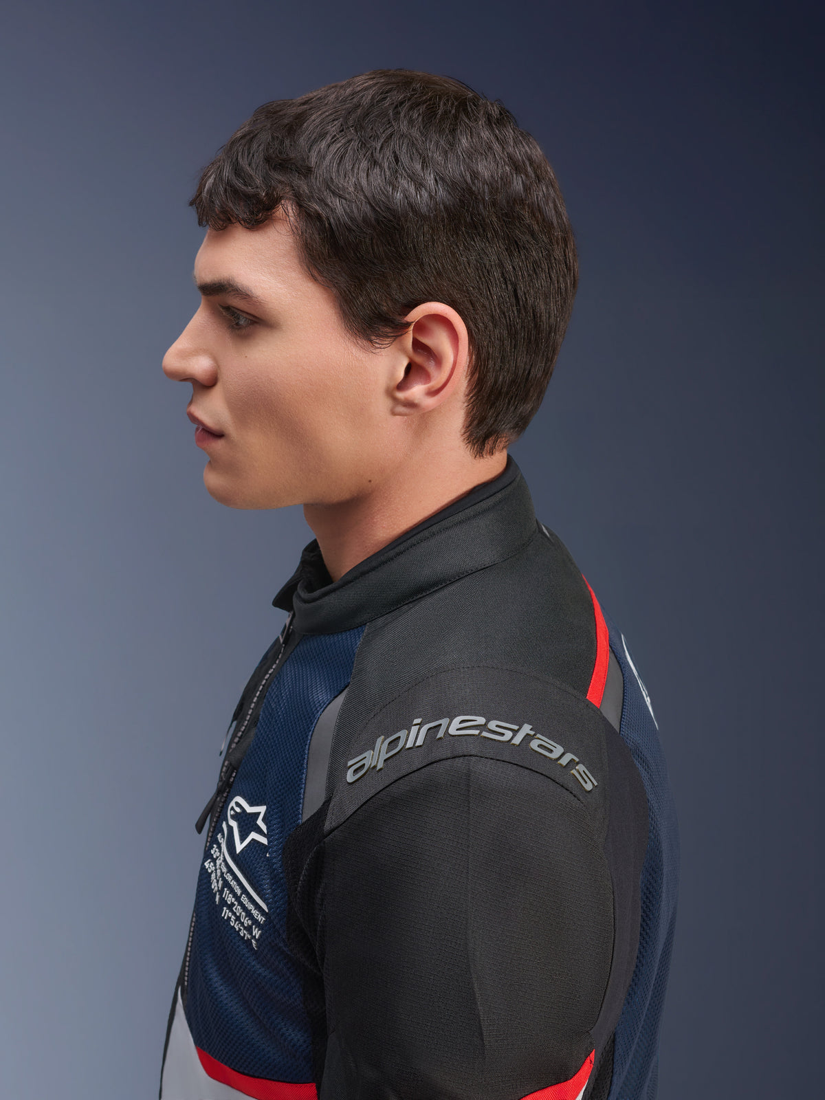 Giacca Alpinestars Andes Air Drystar®, colorazione Deep Blue Black Ice Gray, profilo laterale di un modello maschile che indossa la giacca in tessuto traforato, con marchio Alpinestars sulla spalla e dettagli rossi, abbigliamento touring per due stagioni