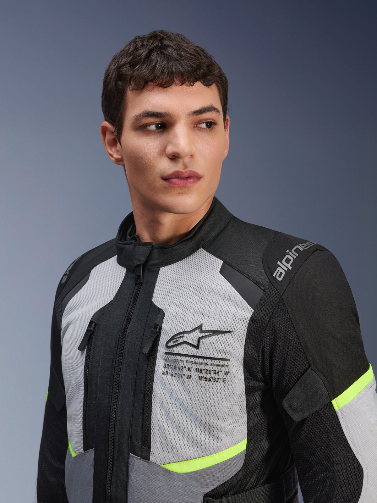 Giacca Alpinestars Andes Air Drystar®, giacca da moto touring, grigio ghiaccio e grigio scuro con accenti giallo neon, indossata da un modello, pannelli in rete 2D per la ventilazione, logo Alpinestars con coordinate sul petto, costruzione in tessuto resistente
