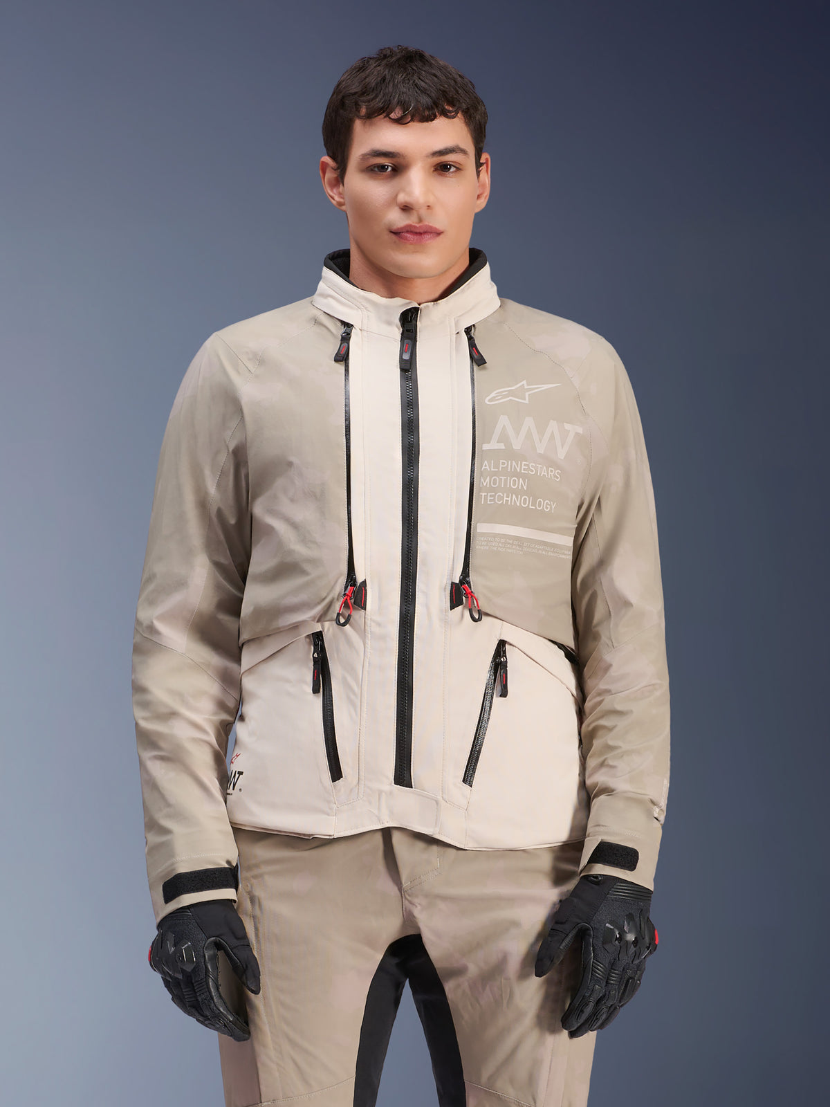 Giacca Alpinestars AMT-10LAB Drystar® XF, giacca da moto adventure, White Sand Aluminum Camo, design modulare con zip nere e dettagli rossi, abbinata a pantaloni coordinati e guanti neri, con marchio Alpinestars Motion Technology sul petto, completo da guida professionale per tutte le stagioni