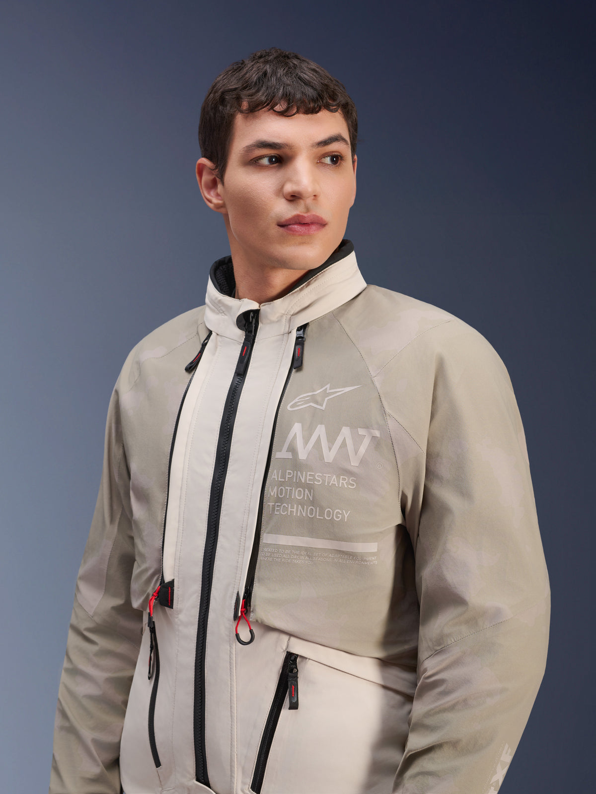 Giacca Alpinestars AMT-10LAB Drystar® XF, White Sand Aluminum Camo, giacca da moto modulare adventure, con marchio "Alpinestars Motion Technology" sul petto, indossata da un modello uomo