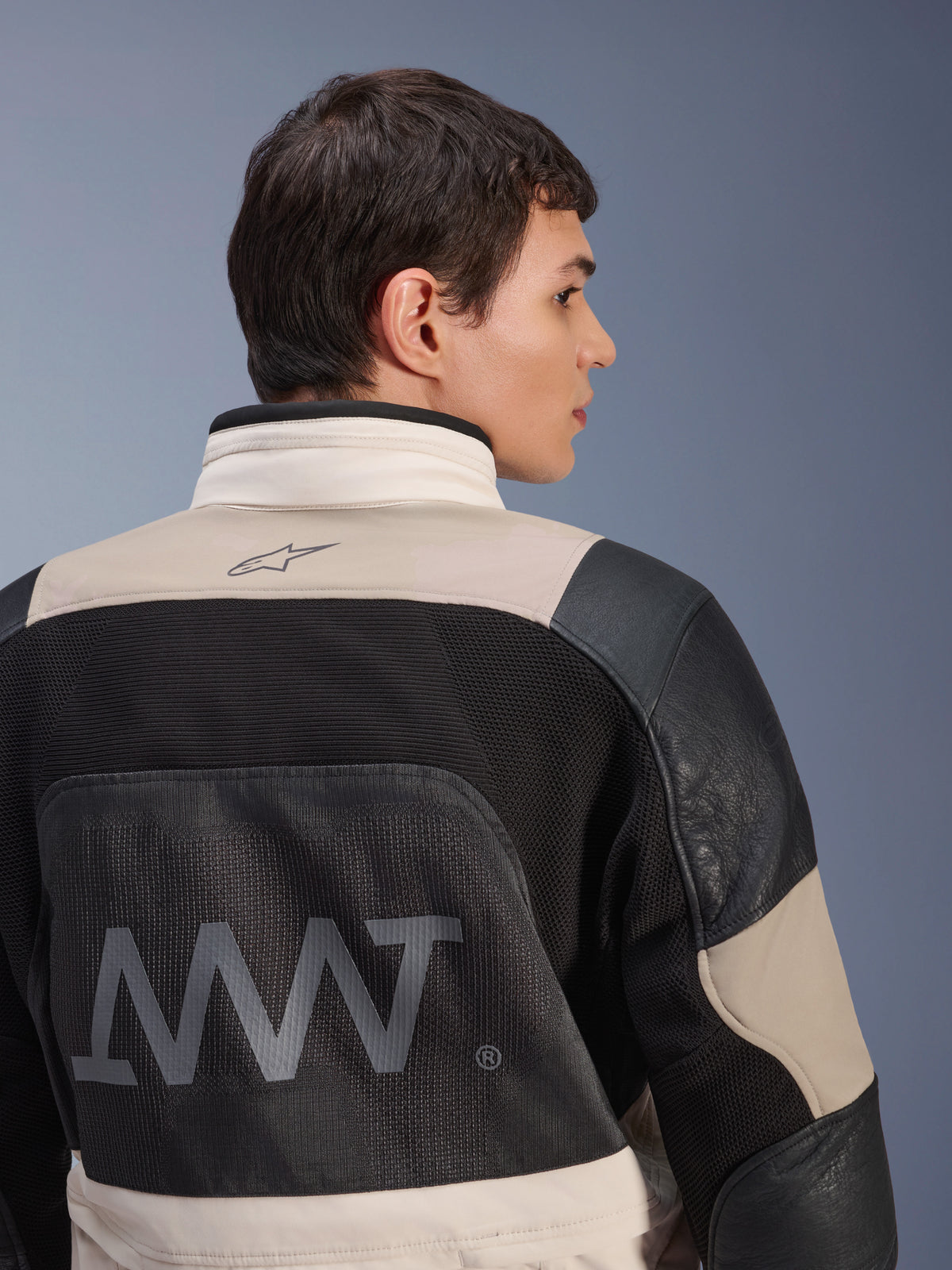 Giacca Alpinestars AMT-10LAB Drystar® XF, vista posteriore su modello maschile, colorazione White Sand Aluminum Camo e nero, con grande marchio AMT, pannelli di ventilazione in rete e rinforzi in pelle, abbigliamento tecnico da moto adventure