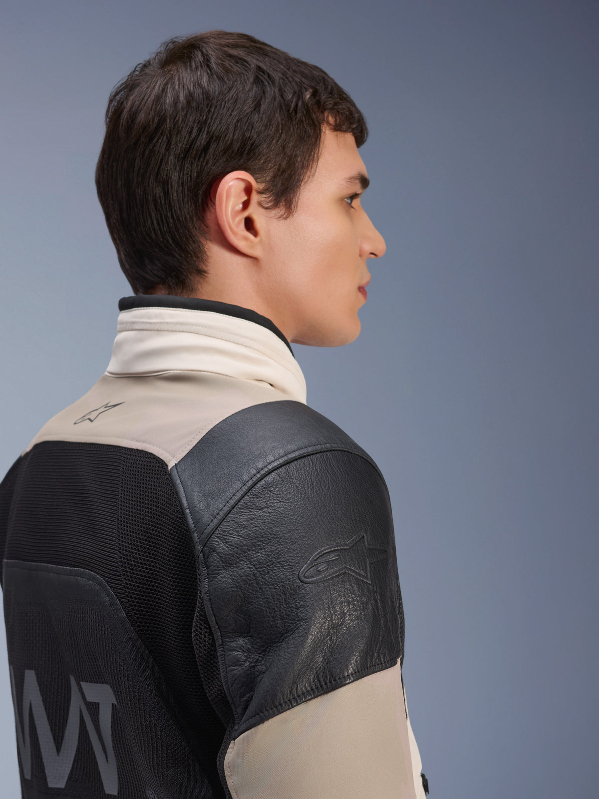 Giacca Alpinestars AMT-10LAB Drystar® XF, giacca da moto adventure, sabbia bianca e nero, profilo laterale che mostra la spalla in pelle nera con logo in rilievo, pannello posteriore in rete MATYRX® con marchio AMT, design protettivo modulare per tutte le condizioni atmosferiche.