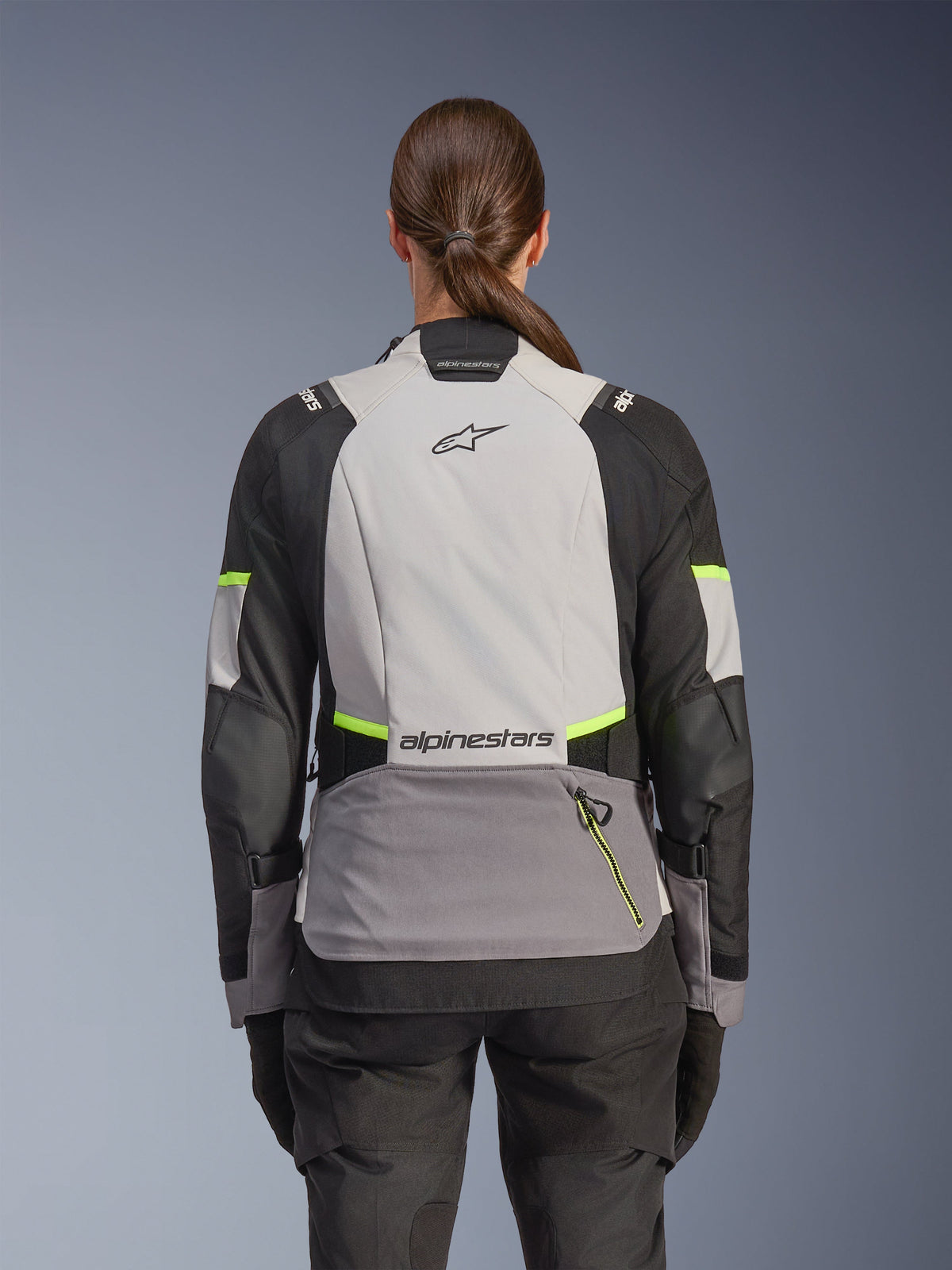 Giacca Alpinestars Stella Andes V4 Drystar®, giacca da moto adventure da donna, vista posteriore, grigio ghiaccio, grigio scuro e nero con accenti giallo fluo, logo Alpinestars sulla schiena, costruzione in tessuto resistente per tutte le stagioni